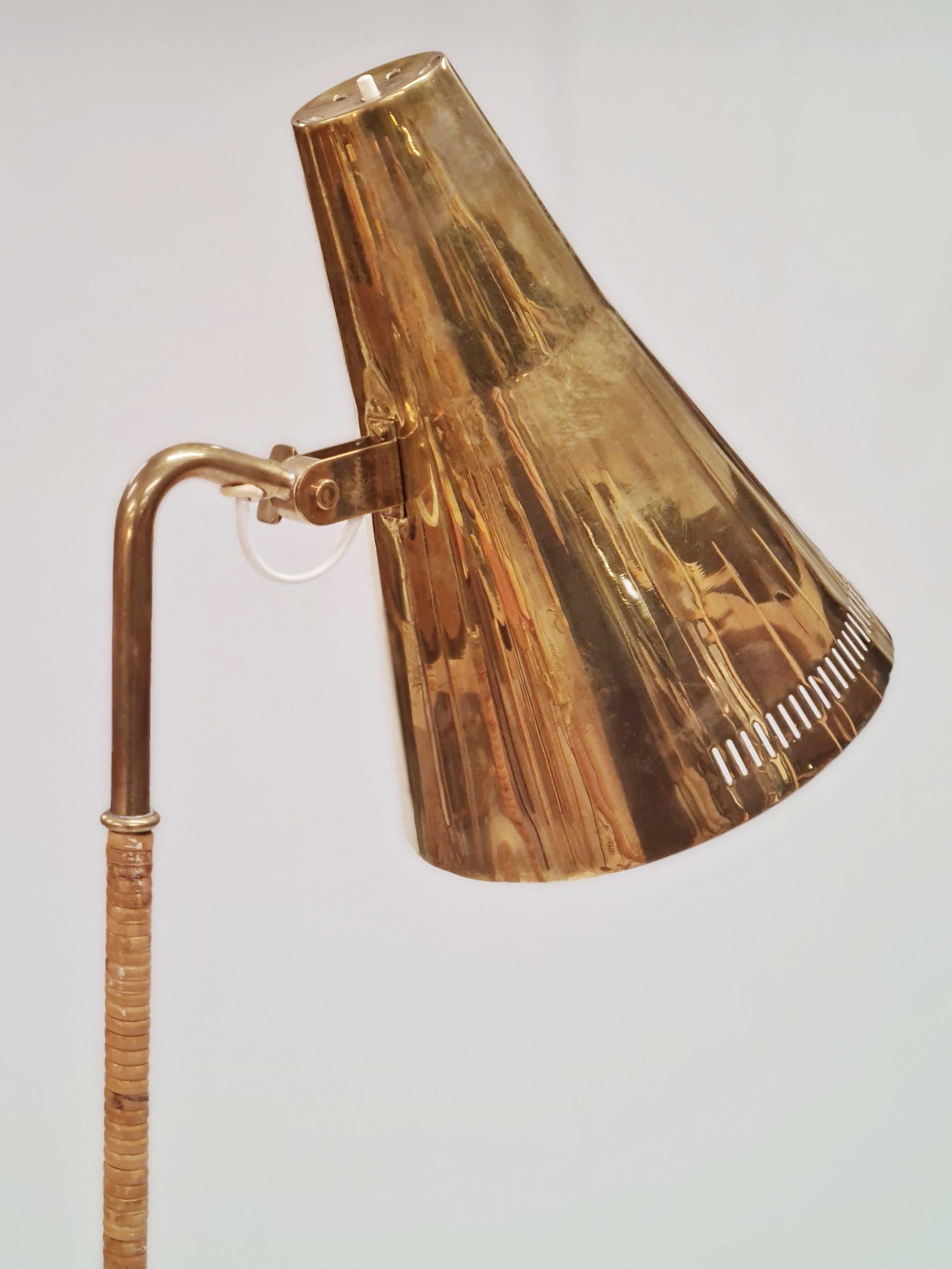 A gracefully slim floor lamp with a solid brass shade and a rattan wrapped stem. A lamp that harmoniously combines the coldness of brass and natural warmth of rattan to create a design that can enhance the finest of interiors, private or