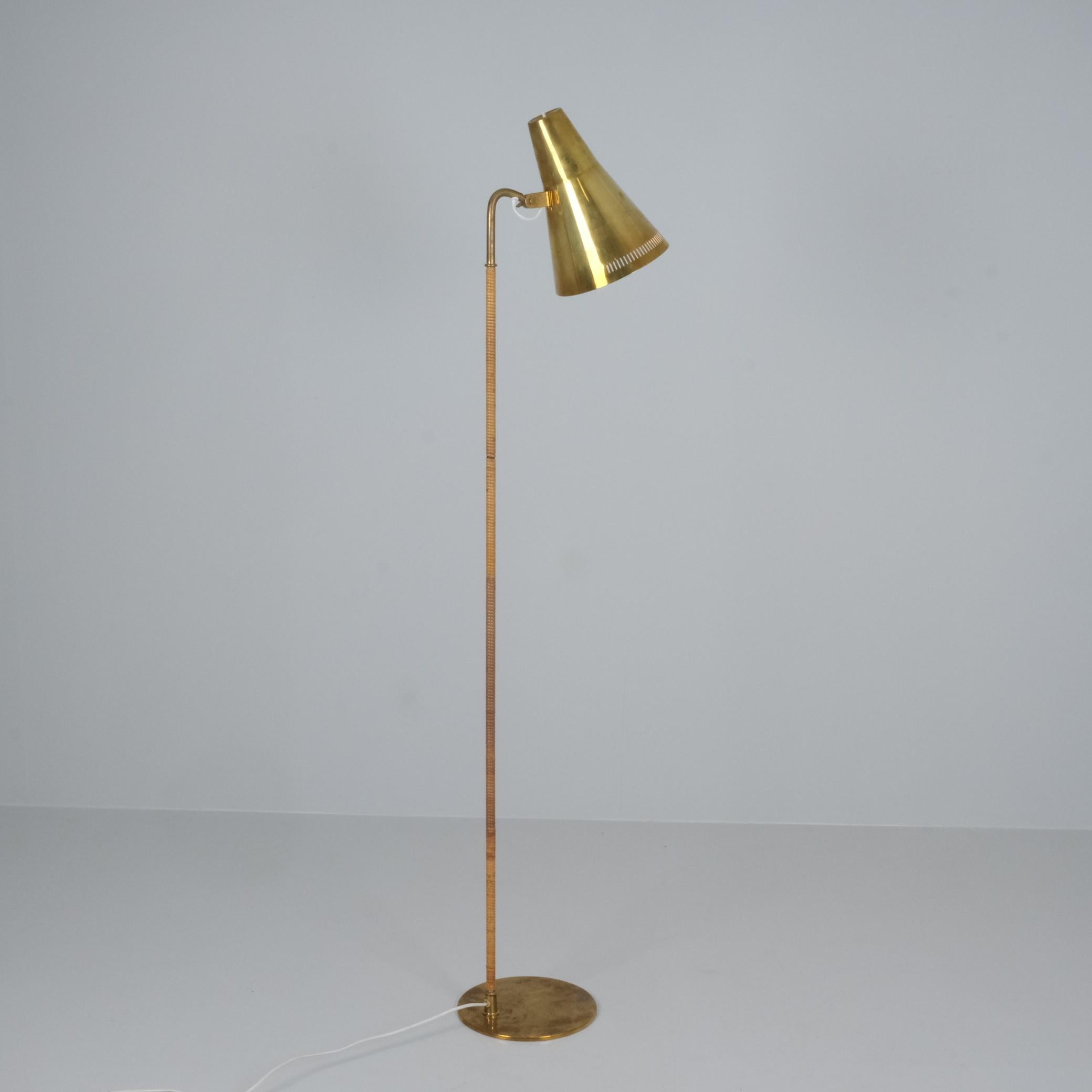 A gracefully slim floor lamp with a solid brass shade and a rattan wrapped stem. The lamp harmoniously combines the coldness of brass and natural warmth of rattan to create a design that can enhance the finest of interiors, private or
