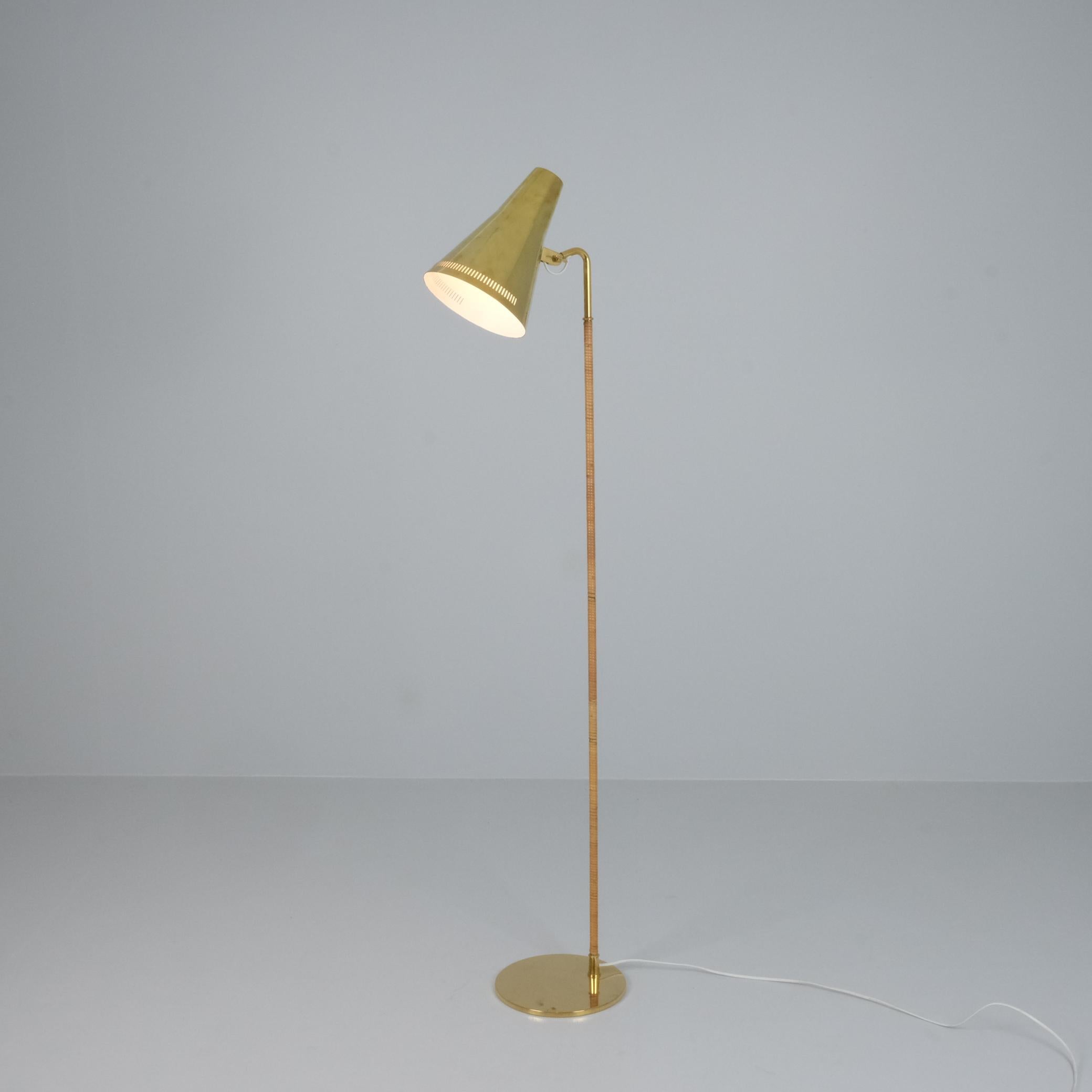 Un lampadaire gracieusement élancé avec un abat-jour en laiton massif et une tige enveloppée de rotin. Cette lampe allie harmonieusement la froideur du laiton et la chaleur naturelle du rotin pour créer un design capable de mettre en valeur les