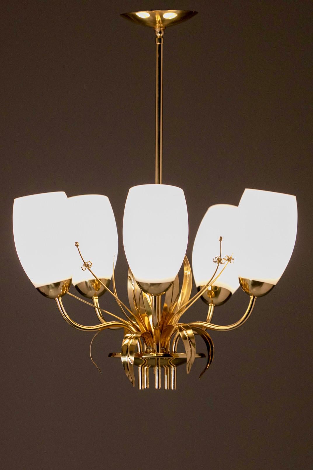 Beautiful 1960s brass and blown glass six arm chandelier by Paavo Tynell for Glashütte Limburg featuring Tynell's organic floral themed details. As if sunning from the glow of the blown glass lights, detailed floral and leaf accents seem to grow and