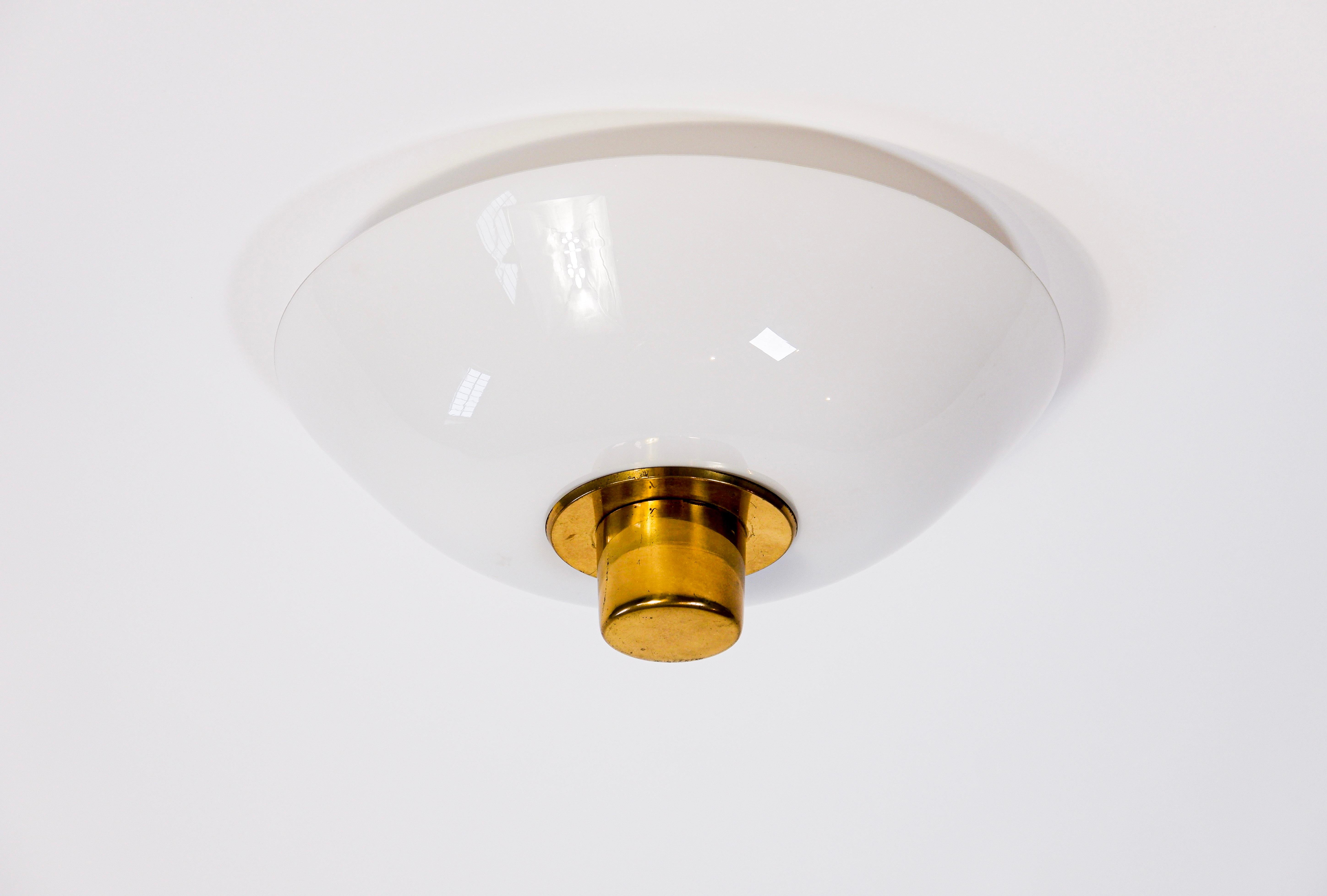 Paavo Tynell flush mount model 2098N made in Opal art glass with a brass decoration on the bottom of the lamp. The lamp is stamp by the editor Idman and has 3 light spots. Good overhall condition. Paavo Tynell is one of the leading designer of the