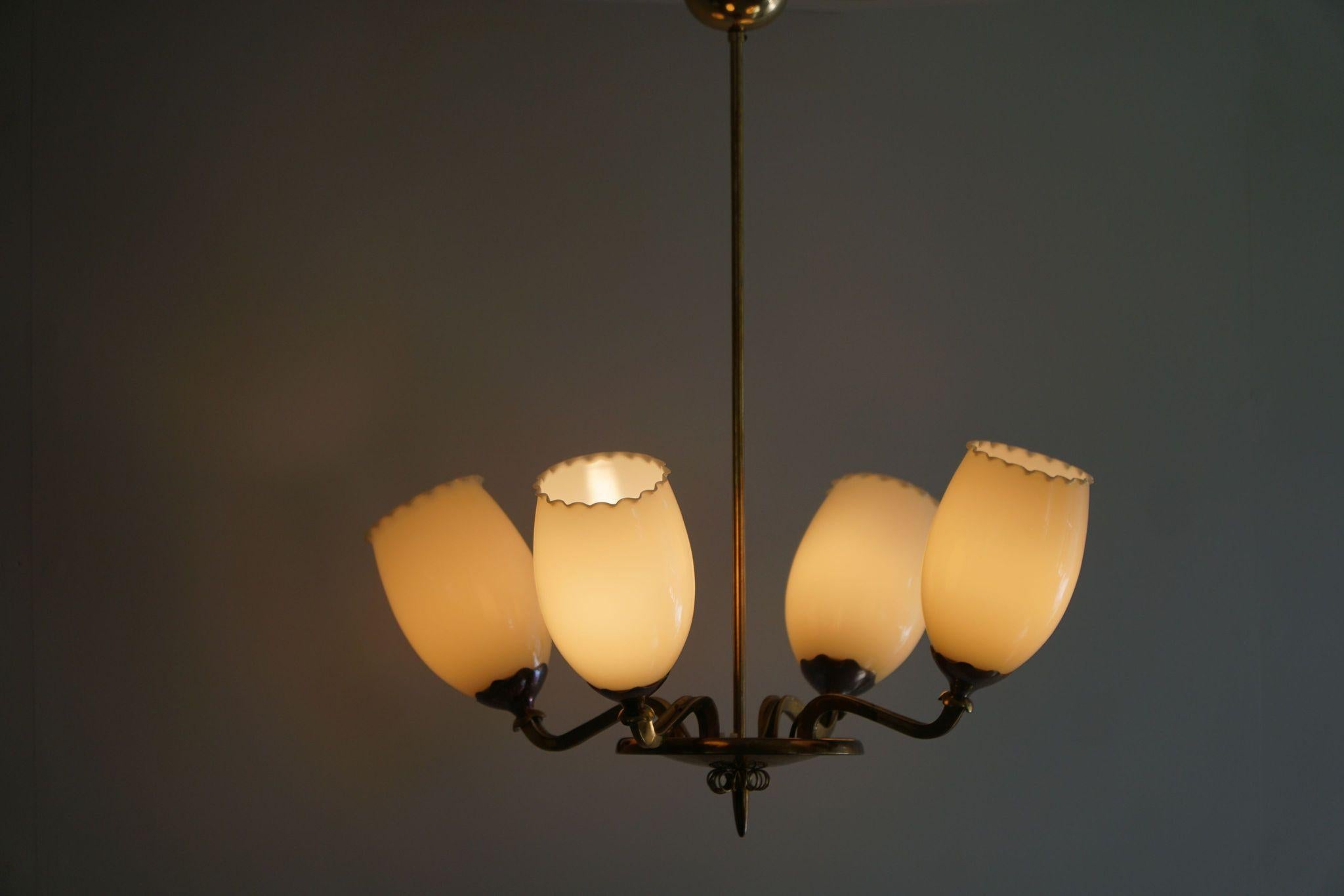 This exquisite chandelier, Model 1382/4, crafted by the renowned Finnish designer Paavo Tynell for Idman OY in the 1940s, is a stunning example of mid-century modern design. The chandelier features a harmonious blend of brass and glass, showcasing