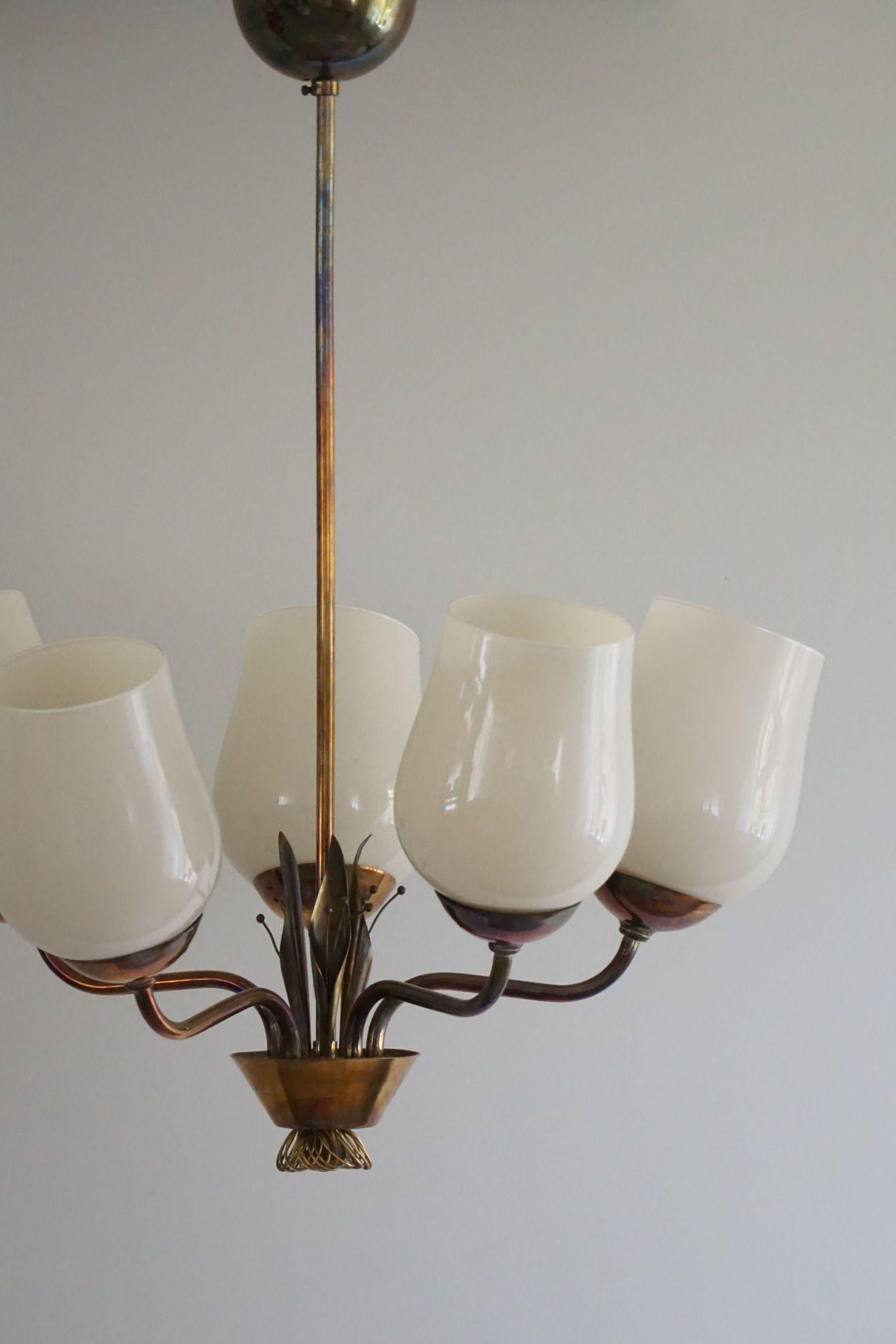 This exquisite chandelier, Model 51145, crafted by the renowned Finnish designer Paavo Tynell for Idman OY in the 1940s, is a stunning example of mid-century modern design. The chandelier features a harmonious blend of brass and glass, showcasing