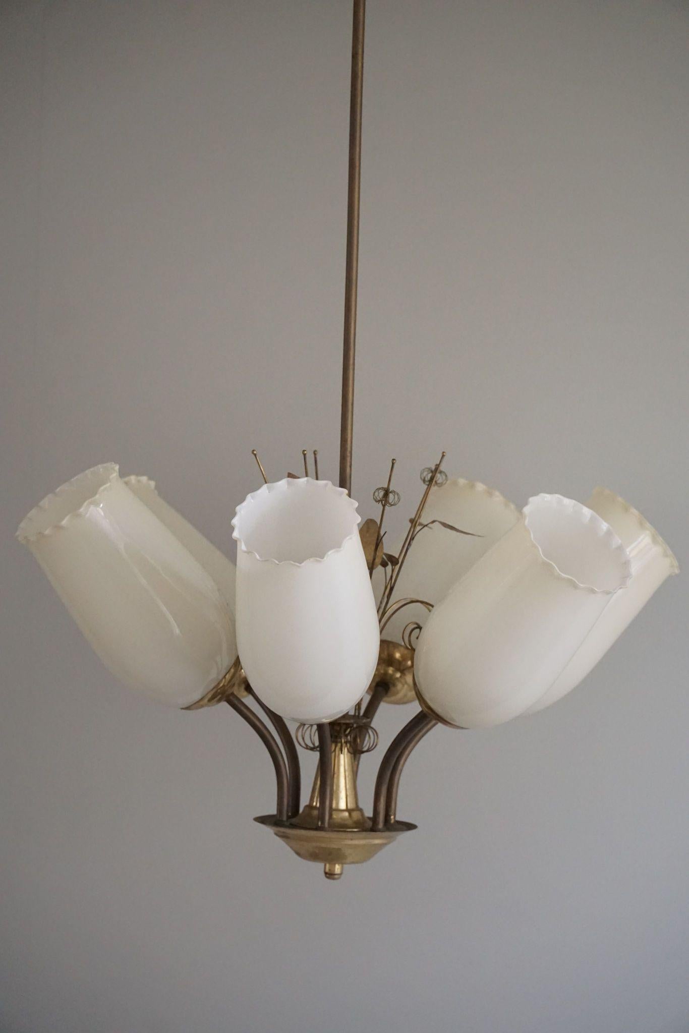 This fantastic 1940s chandelier by Paavo Tynell, designed for Idman Oy, is a masterful blend of elegance and whimsy. Crafted from brass, it features six graceful arms extending from a central stem adorned with delicate brass leaves, adding a