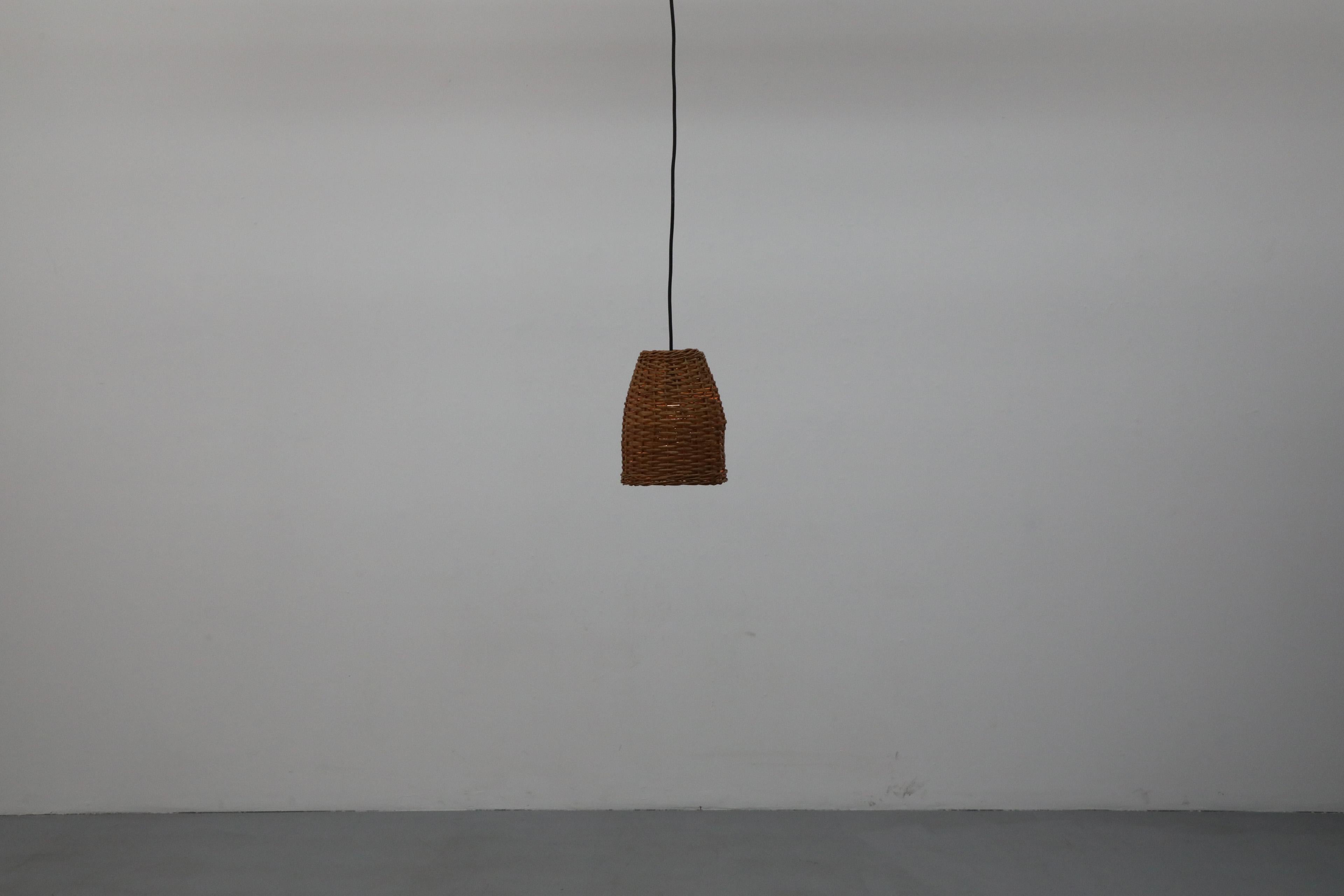 Lampada a sospensione di metà secolo realizzata alla maniera del famoso designer finlandese Paavo Tynell con rattan sapientemente intrecciato a mano. Ha ancora il suo tettuccio originale europeo in plastica nera ed è in buone condizioni originali.