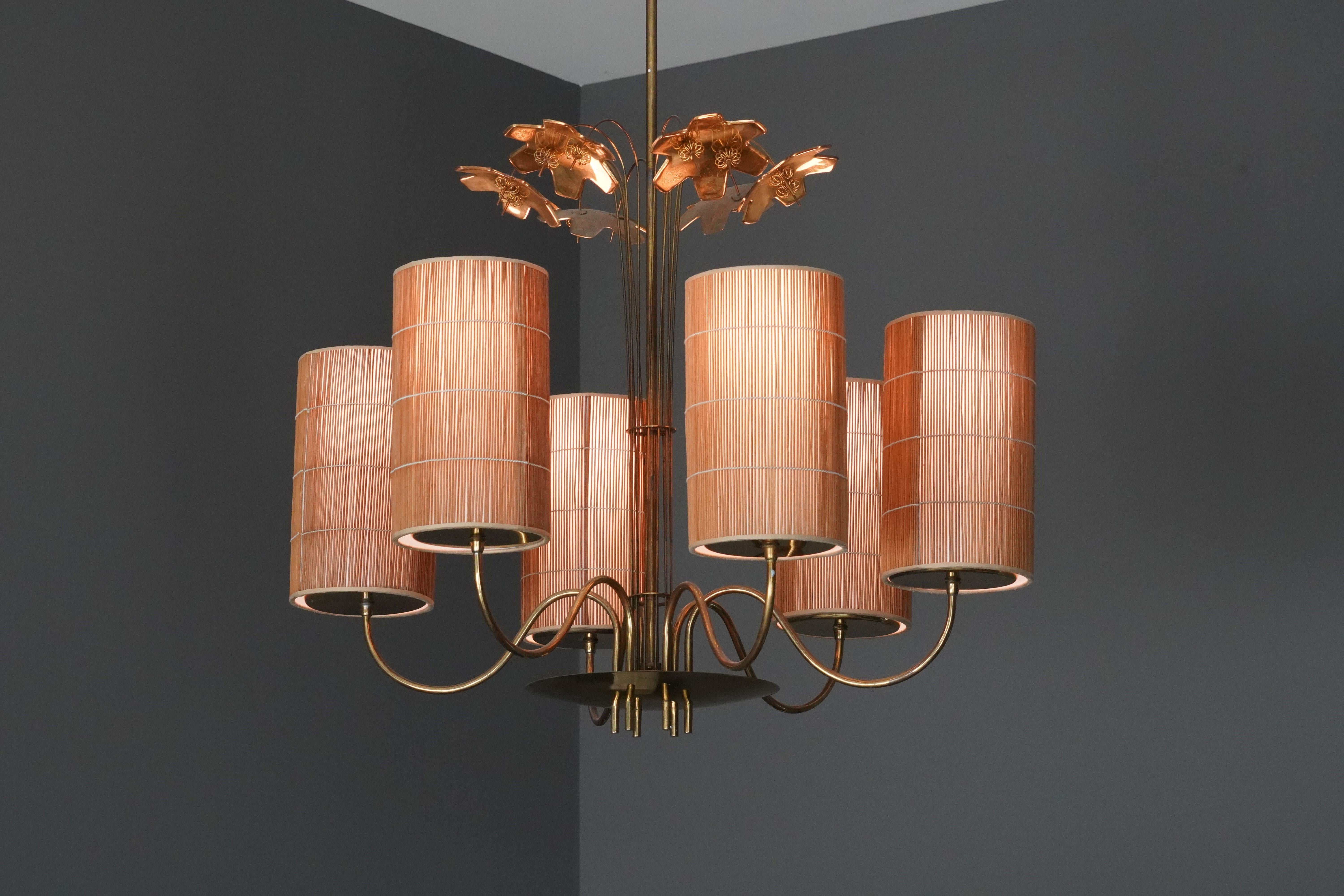 A large chandelier / ceiling lamp in brass by Finnish designer Paavo Tynell. Decorated with six snowflakes. Produced by Tynell's firm, Taito OY. Handmade reed shades of later production. Six light sources.

Starting as a jewelry designer, Paavo