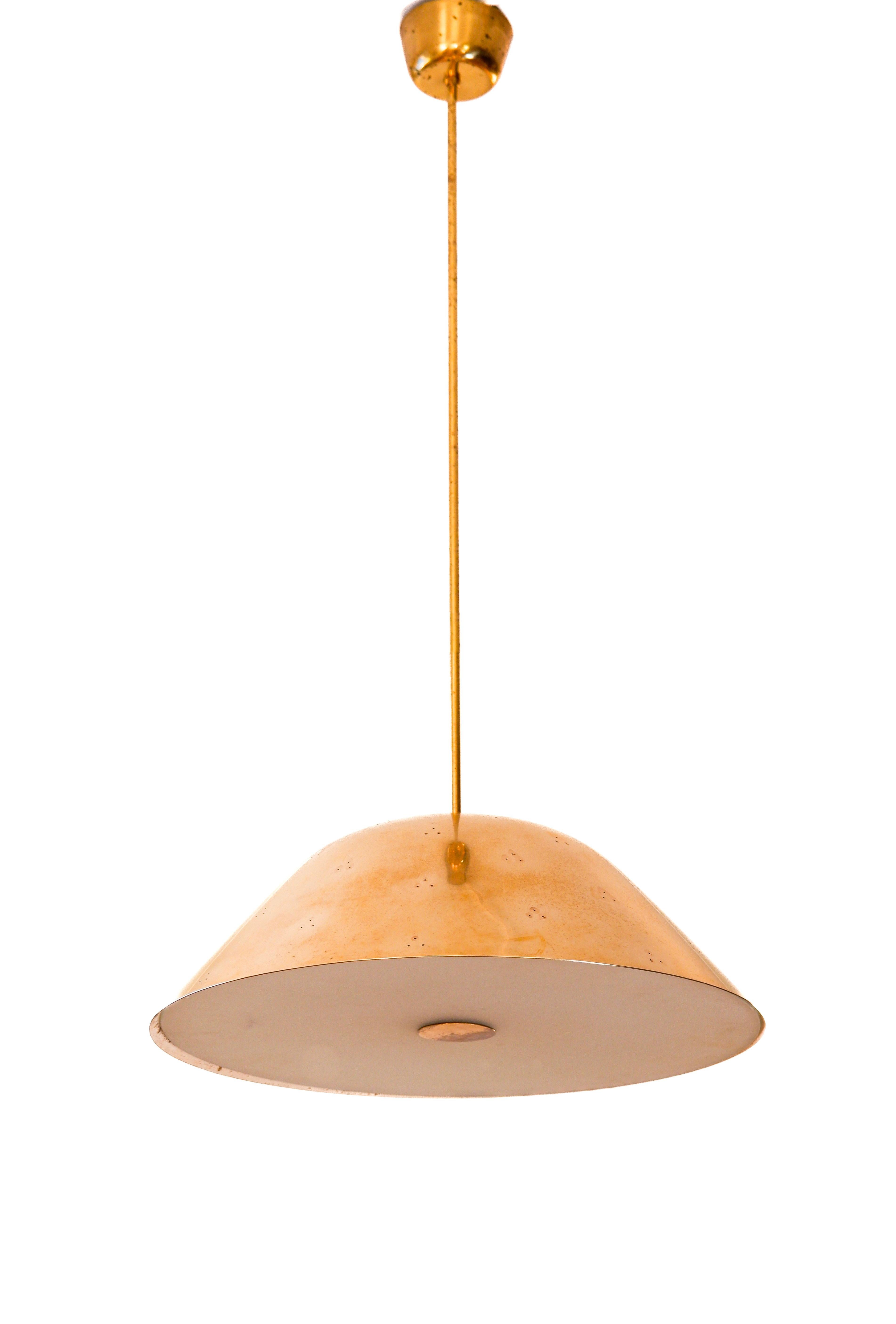 Grand plafonnier Paavo Tynell en laiton massif, composé d'un abat-jour perforé et d'un diffuseur en verre. La lampe est en très bon état. Le tuyau peut être coupé si nécessaire. Paavo Tynell est l'un des designers scandinaves les plus influents du