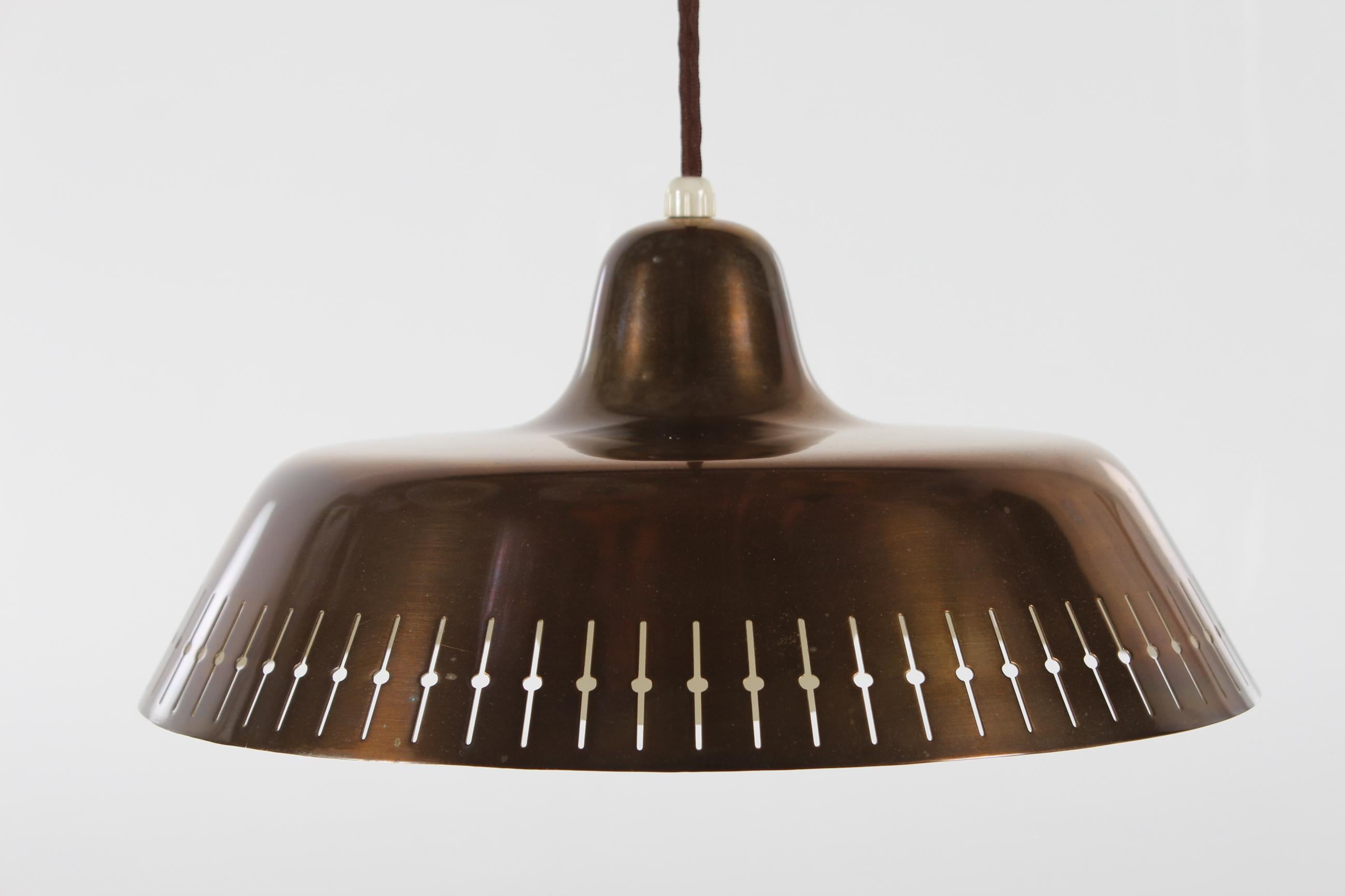 This pendant is made of brass with a fine patina on the surface, a patina developed from gentle use over time. The inside of the pendant has white lacquer.
The perforated pattern along the rim give a nice and pleasant light effect.
The light bulb