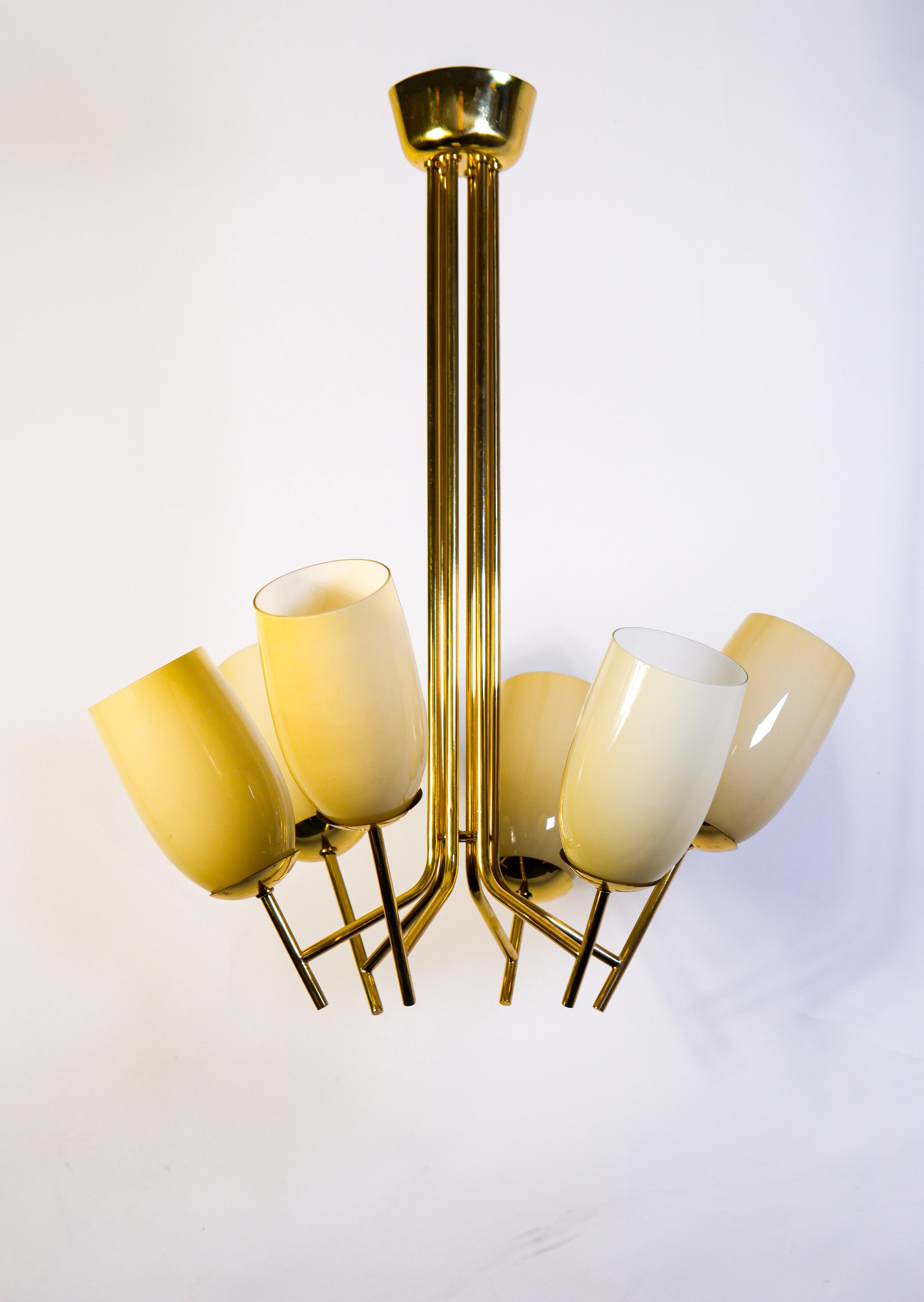 Rare chandelier design by Paavo Tynell for Taito, circa 1950. The chandelier is composed by a solid brass core with 6 arms disposed in two levels up and down of each other. Each arm has its own opal glass shade. Good overhall condition. The lamp is