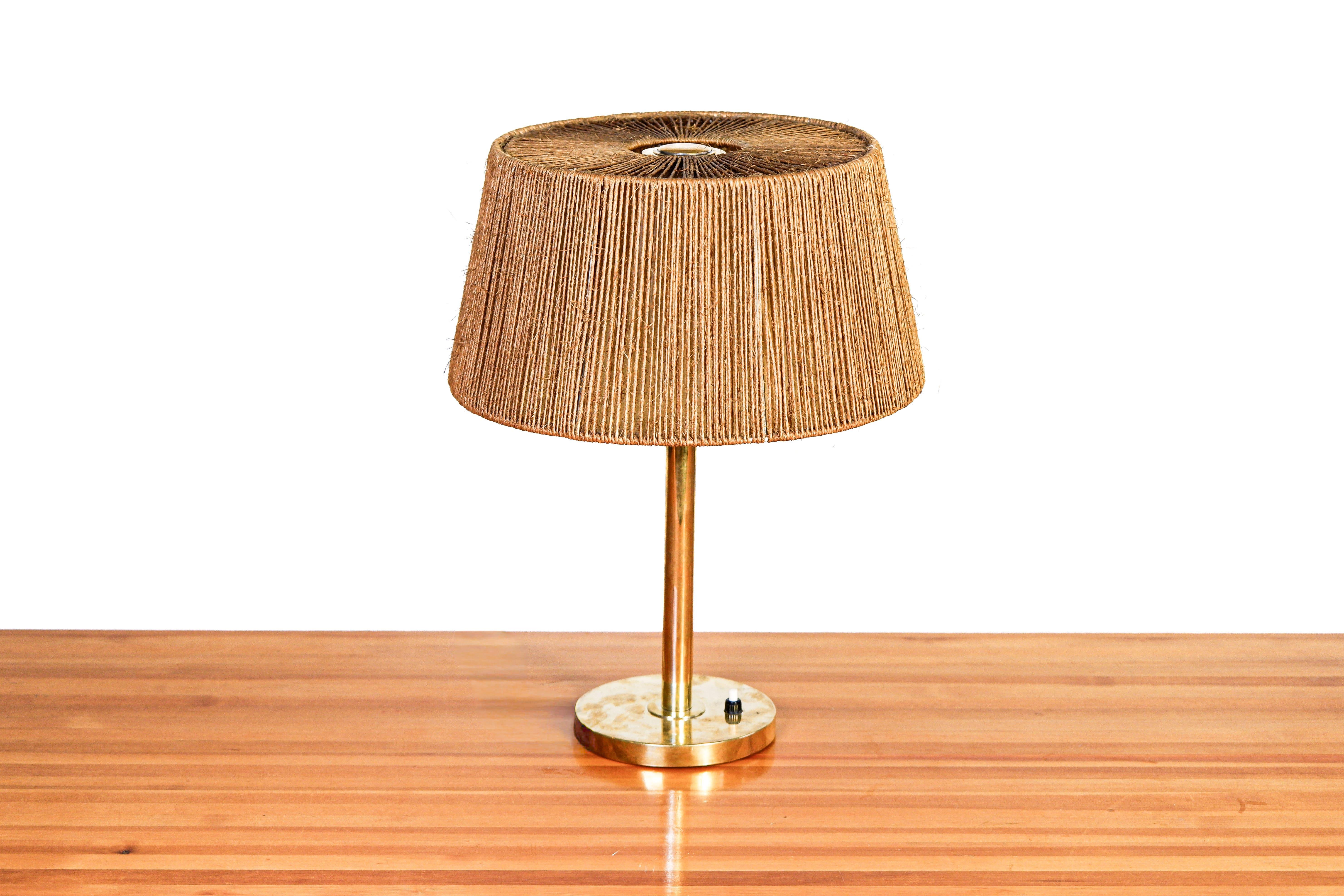 Paavo Tynell Tischlampe Modell 5144 für Taito, hergestellt aus massivem Messing mit einem originalen Schirm aus den 40er Jahren aus Corde. Die Lampe ist in gutem Zustand und seine Marke vom Herausgeber Taito. Paavo Tynell ist neben Alvar Aalto oder