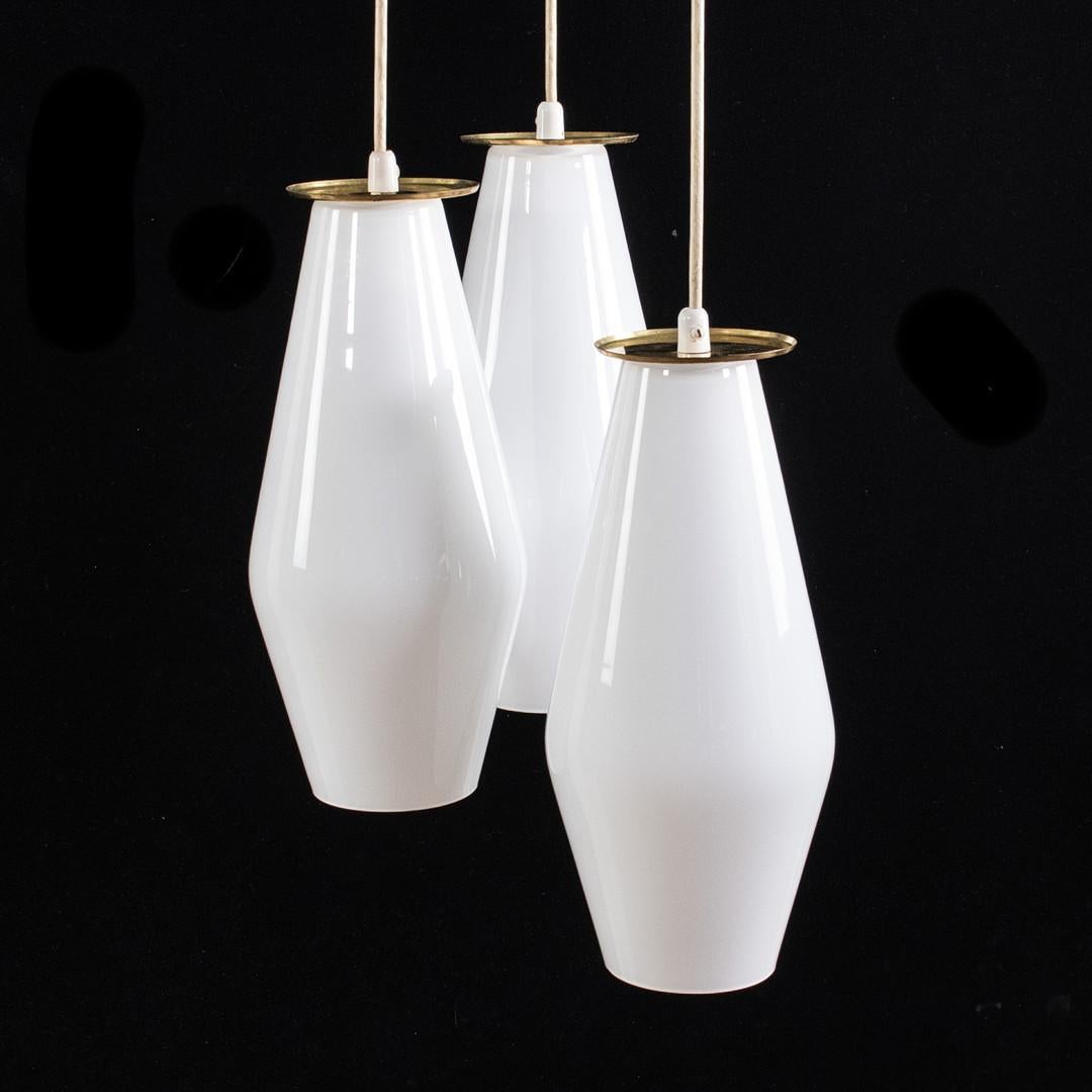 Trois lampes en verre opale avec détails en laiton, suspension réglable en hauteur, hauteur de la coupelle environ 36 cm, diamètre 14 cm.
Conçu en Finlande par Paavo Tynell dans les années 1950 pour Idman Oy.
