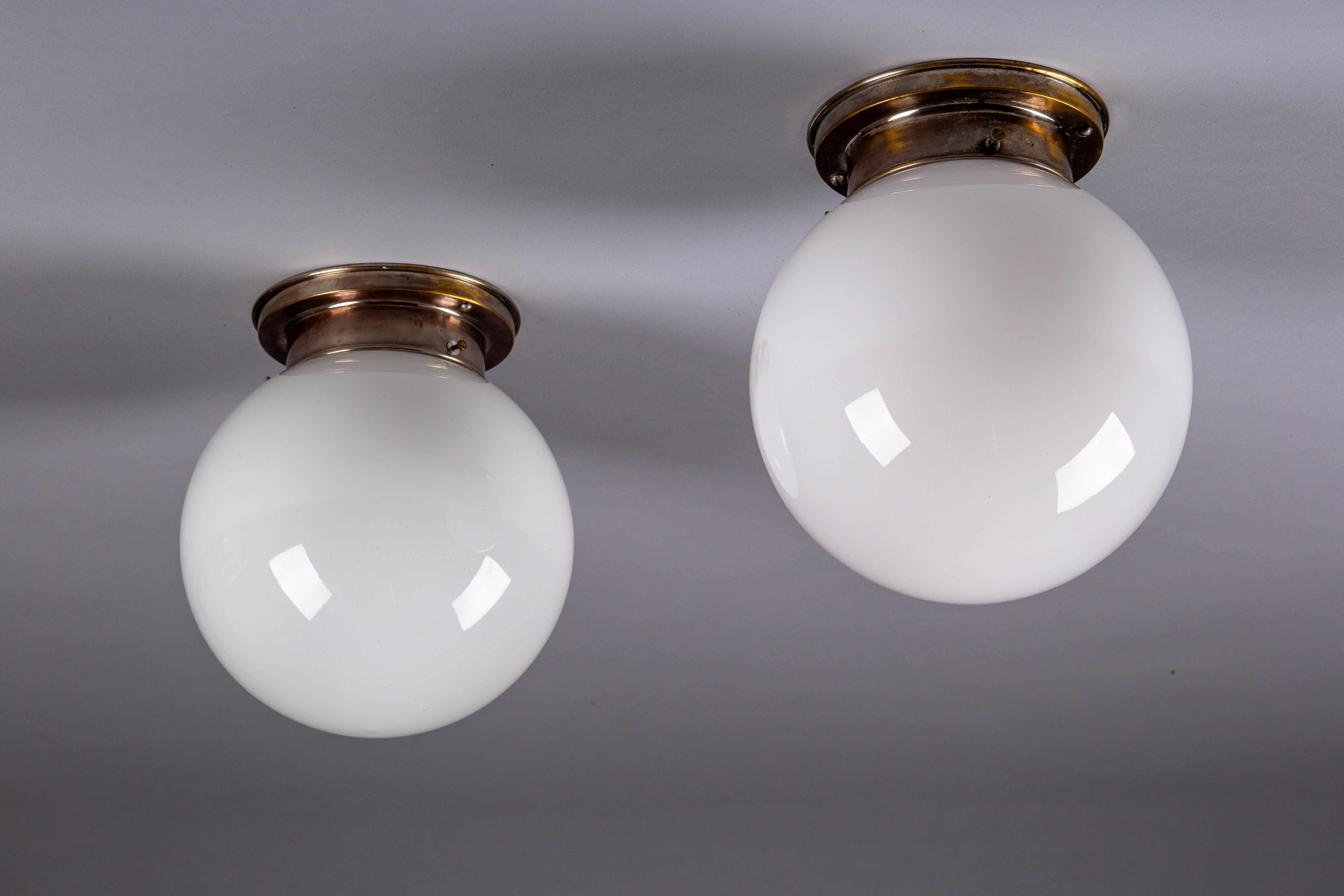 Discover the timeless elegance of our set of 1930's opaline glass sphere flush mount lamps by Paavo Tynell for Idman Oy. These versatile lamps are perfect for adding a touch of vintage sophistication to your hallway or powder room. Each piece