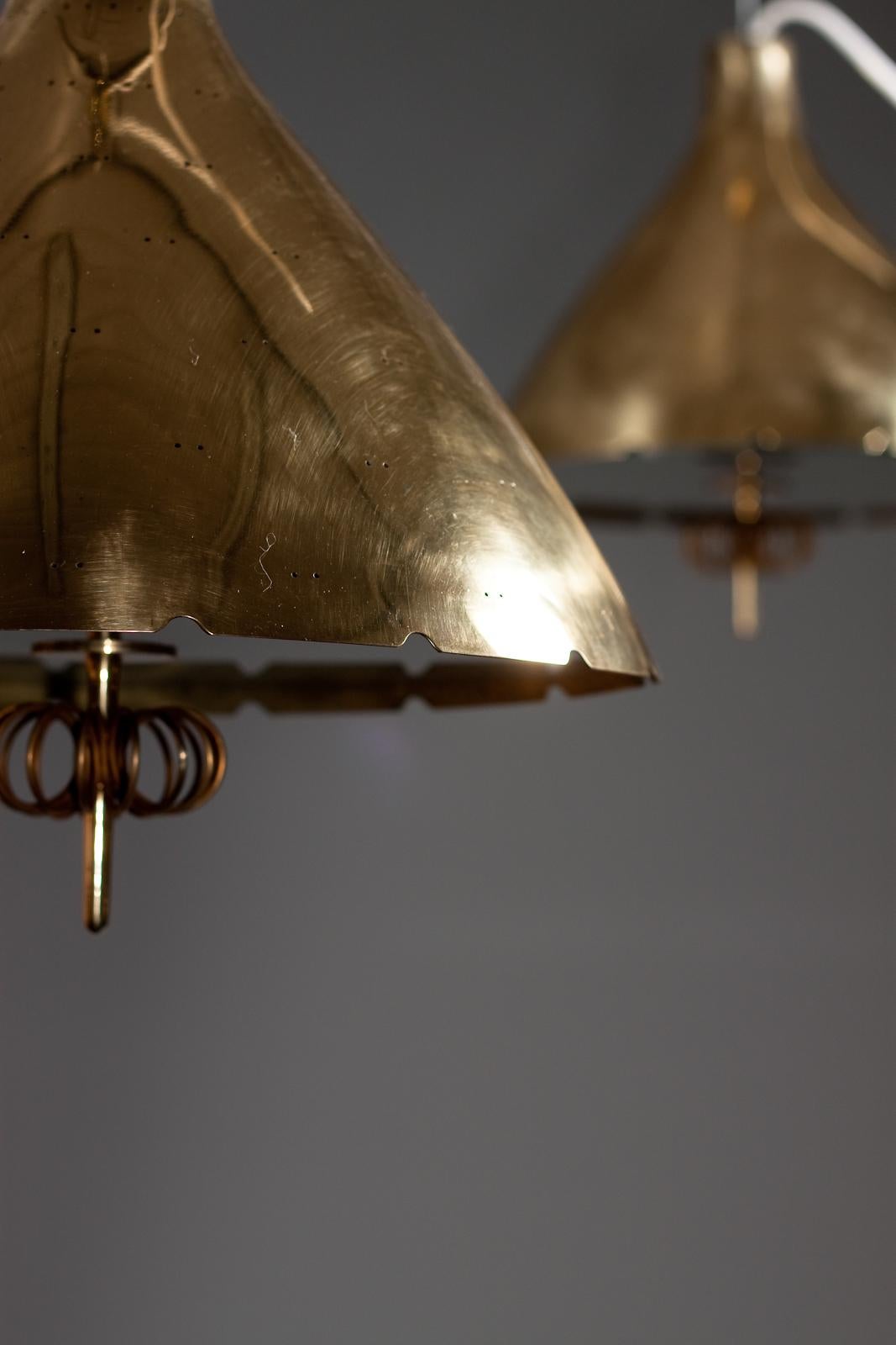 Introducing a stunning pair of 1940's brass counterweight pendant lamps by Paavo Tynell for Taito Oy. With their elegantly crafted brass composition and unique counterweight elevating system, these lamps exude vintage charm and sophistication. Each