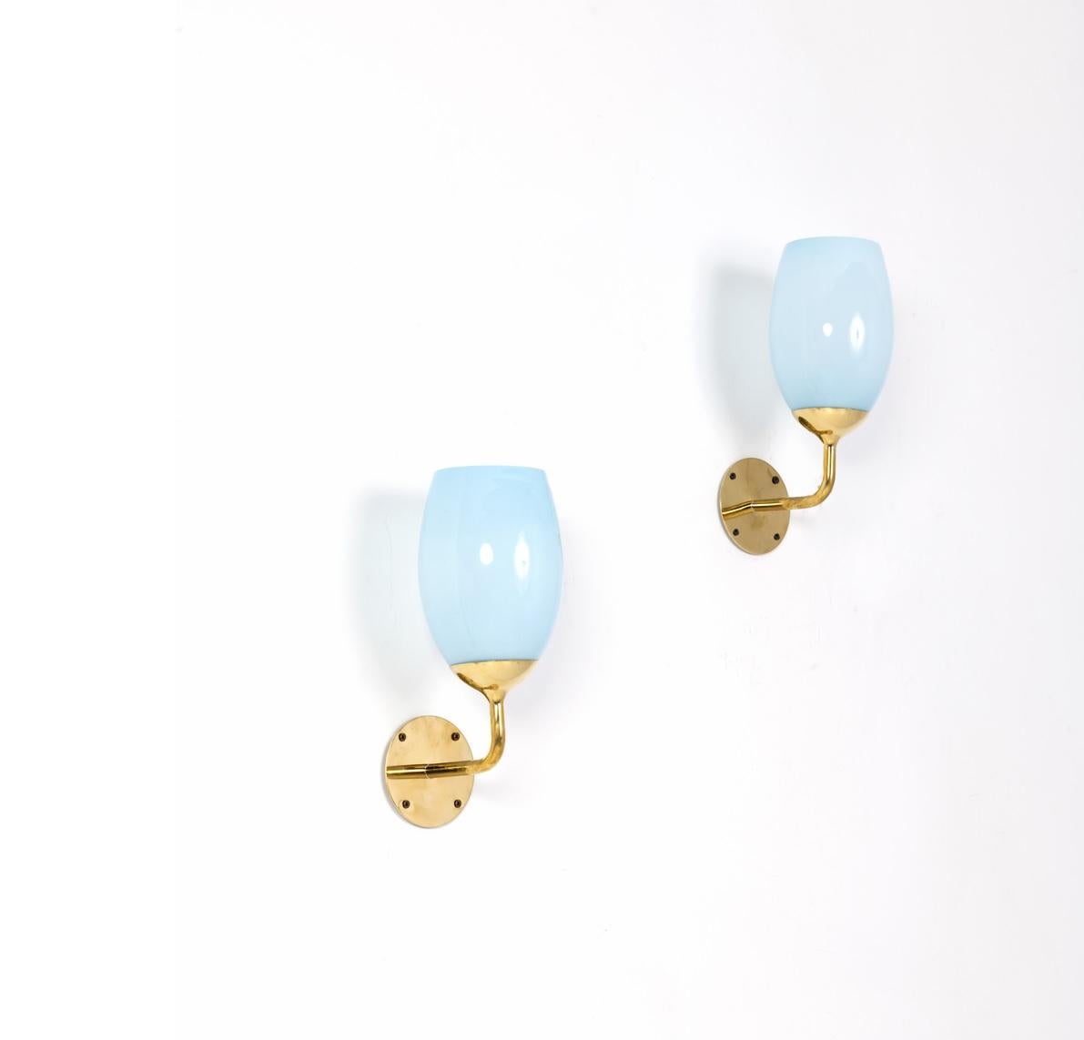 Pair of Paavo Tynell wall lights in brass and light blue glass for Taito Oy, Finland, 1940s.

Provenance: Kontiolax, Finland

Glass is in excellent condition with no chips or cracks. Height is 18 inches (44 cm).

Price is for the pair of lamps.