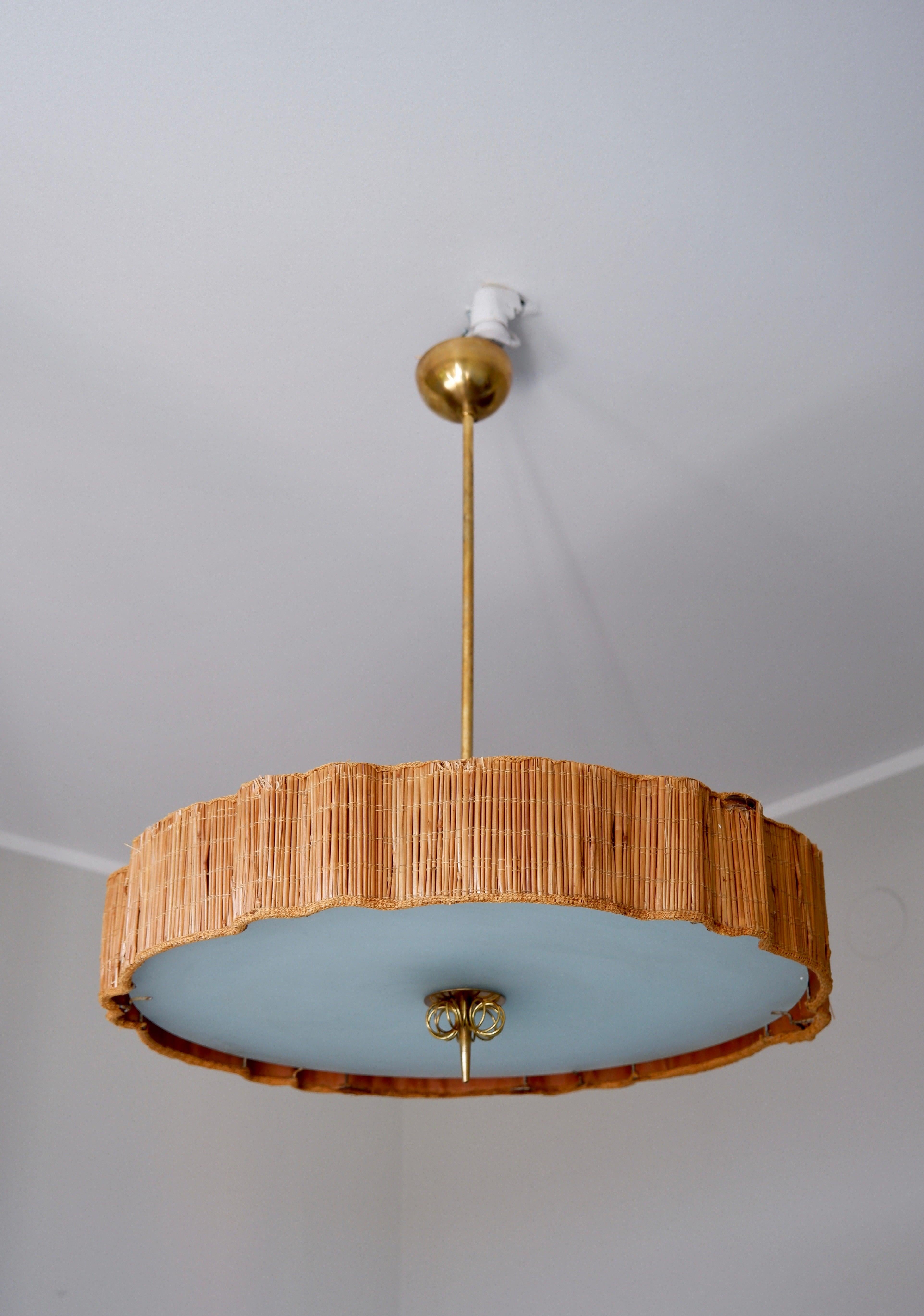 Nice Paavo Tynell ceiling ligth made with rattan straw shade, glass and brass. This lamp is using every aspect of Paavo Tynell style, the straw rattan shade preserves scandinavian tradition, both the glass and the brass brings a modernity aspect to