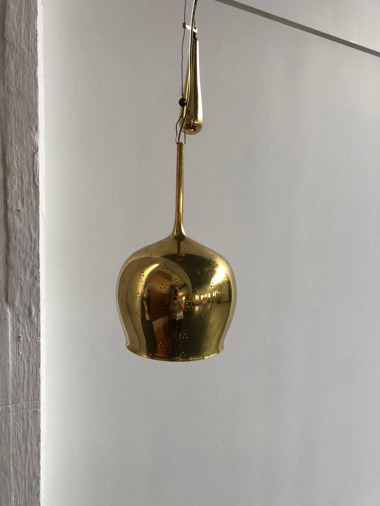 Paavo Tynell pendant in perforated brass with counter weight. Has adjustable height. Made by Taito Oy, Finland, 1950s. Marked from the manufactorer on top part.