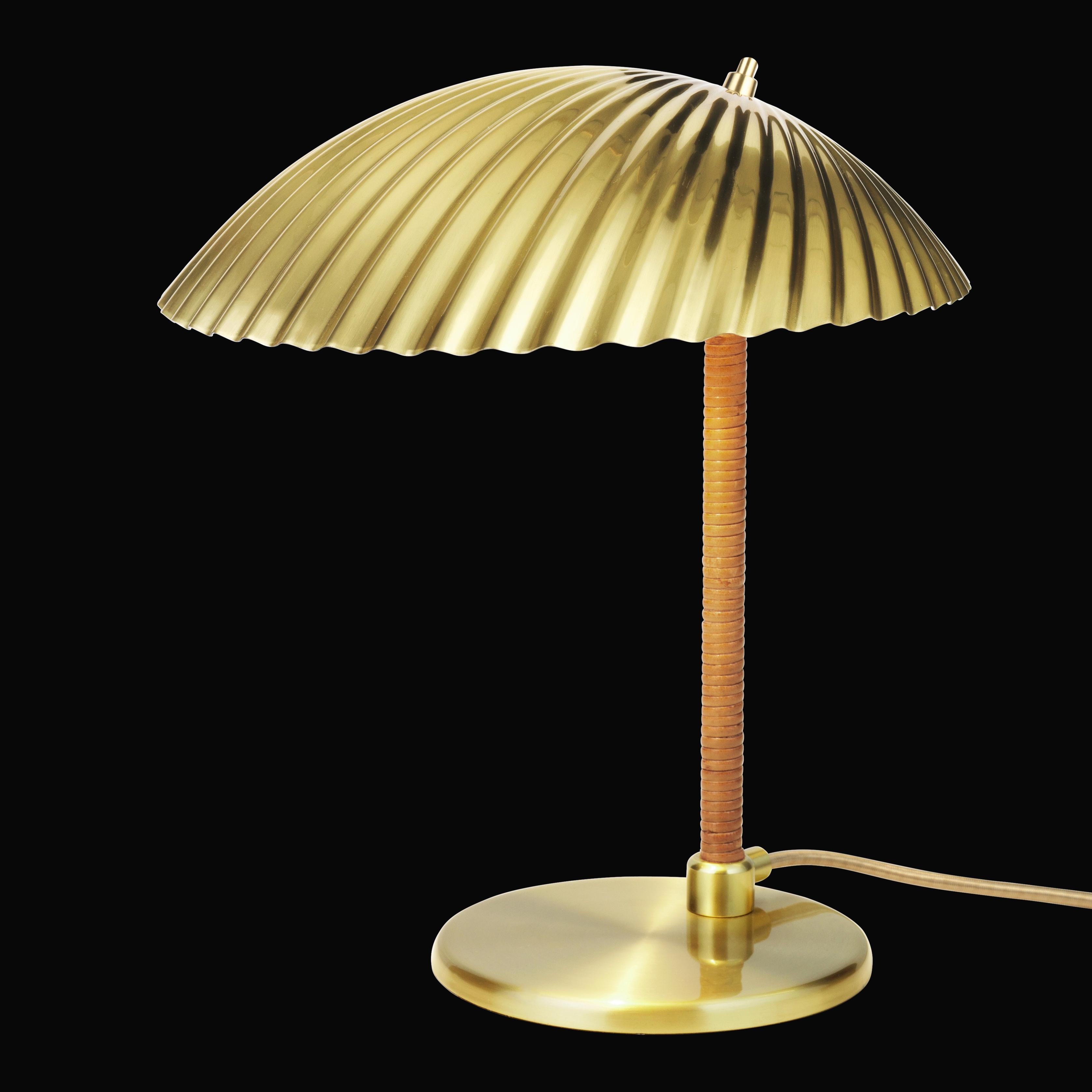Designed by the Finnish designer Paavo Tynell in 1938, this Classic brass and rattan table lamp marks the early stages of Mid-Century Modernism, combining graceful simplicity with the elegant influence of nature in one design. This piece is a