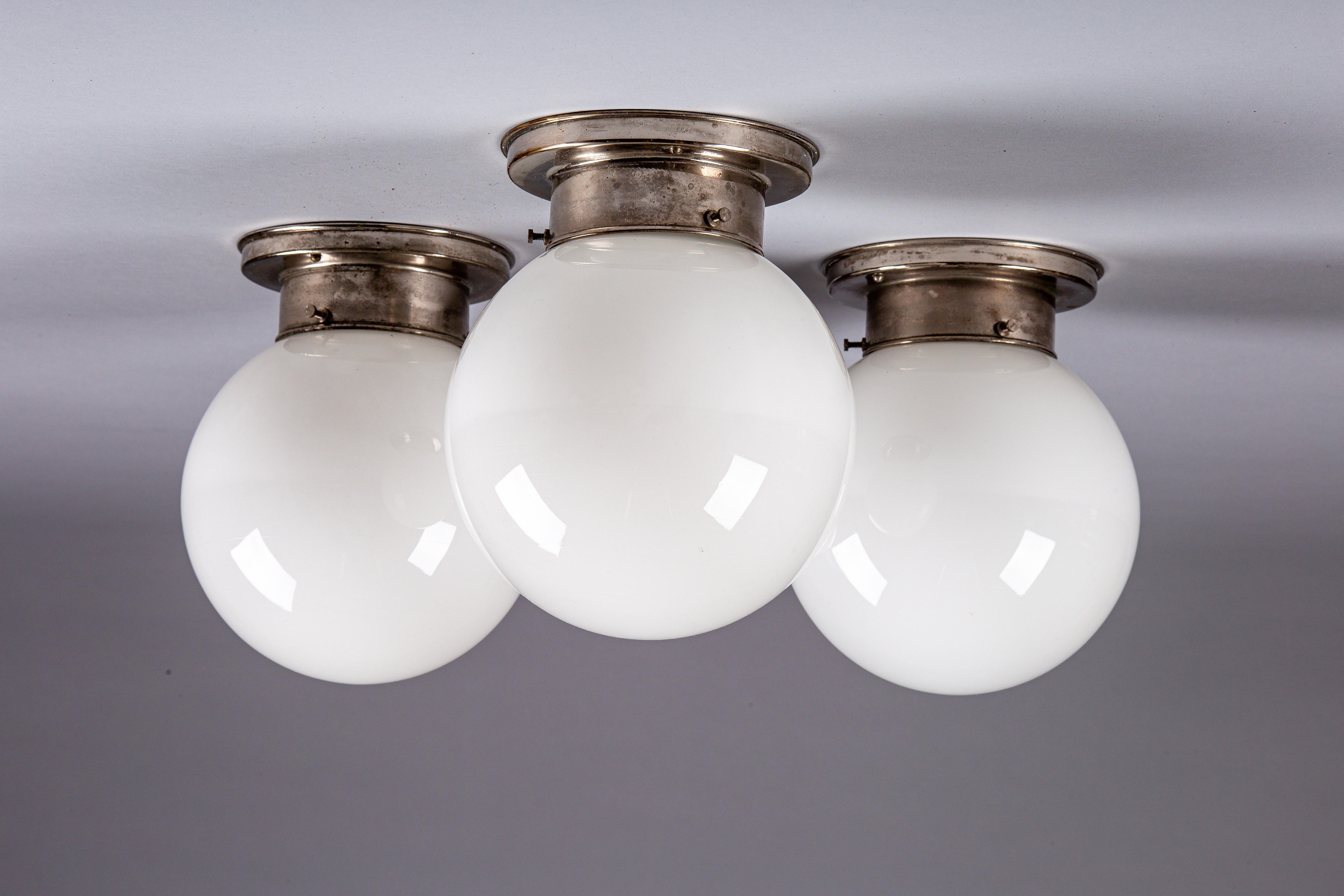 Discover the timeless elegance of our set of 1930's opaline glass sphere flush mount lamps by Paavo Tynell for Idman Oy. These versatile lamps are perfect for adding a touch of vintage sophistication to your hallway or powder room. Each piece