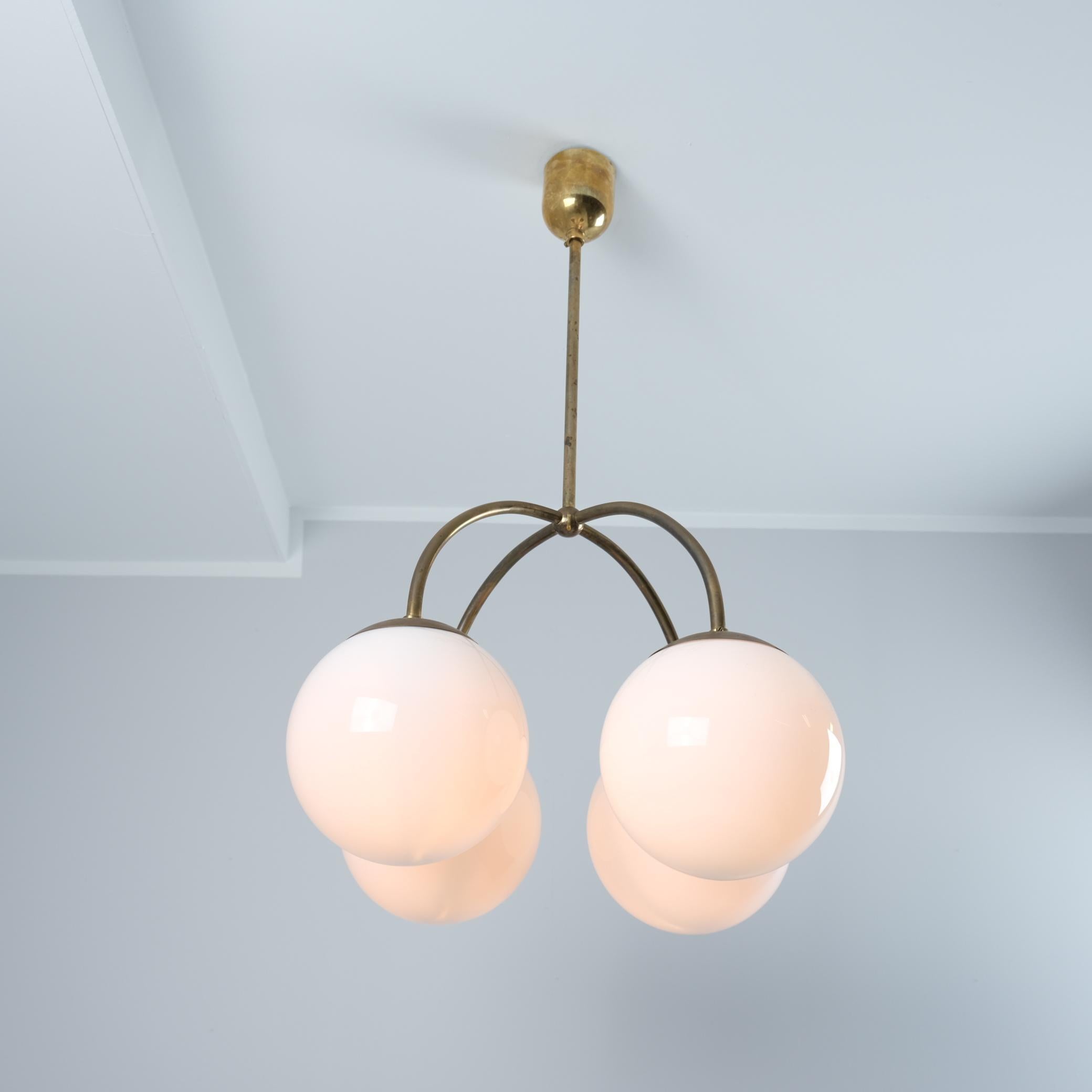 Un bellissimo e raro esempio di lampade minimaliste funzionaliste di Paavo Tynell degli anni Trenta. Un gruppo di 4 paralumi a sfera bianchi opalini che pendono da un corpo minimalista in ottone. Un design semplice ma di grande effetto che porta con