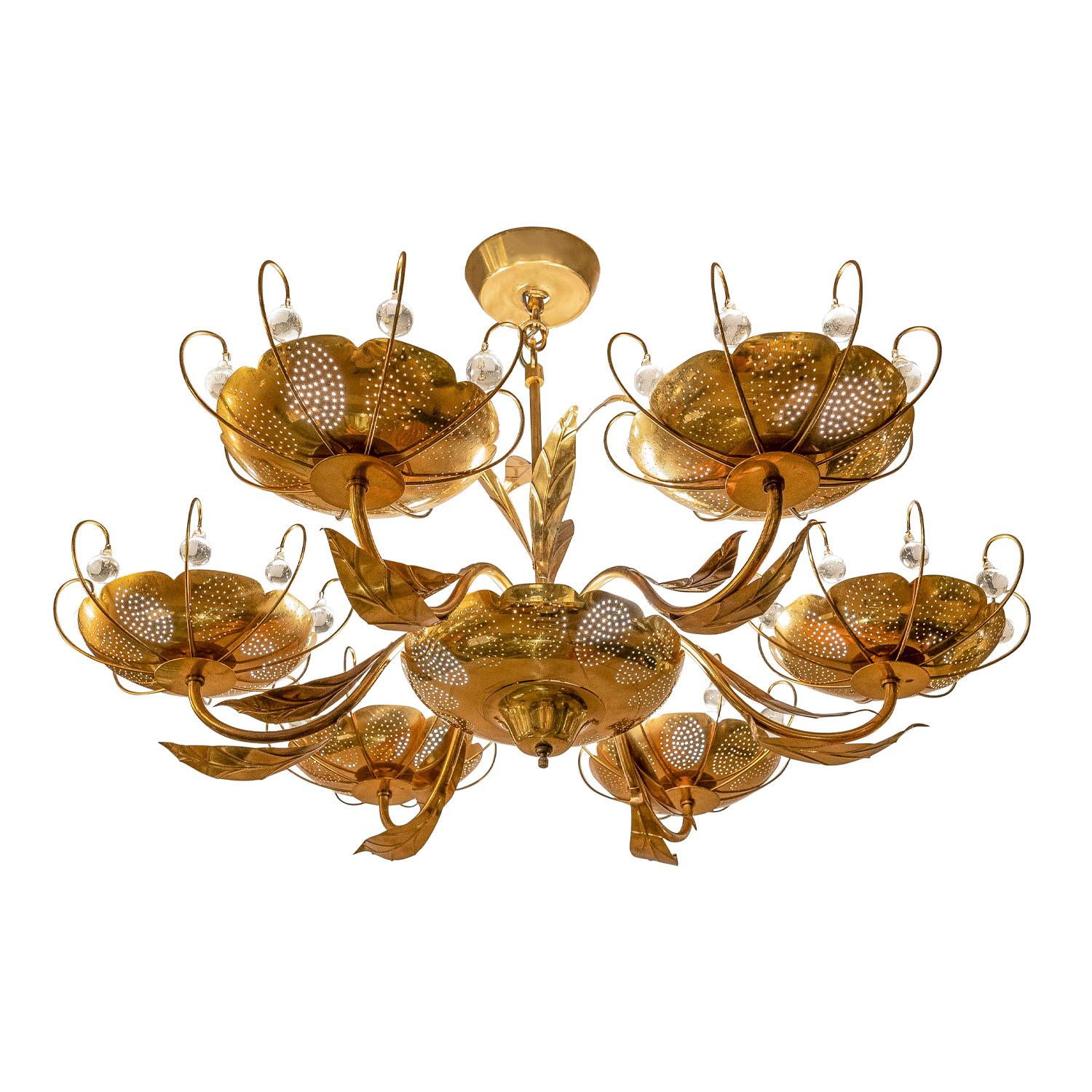 Six arm chandelier in brass with leaves and perforated bobeches, each with suspended crystal orbs, in the style of Paavo Tynell, American 1960's.  The organic motif is beautiful and the crystals add a little glamor.  There is a switch on the bottom