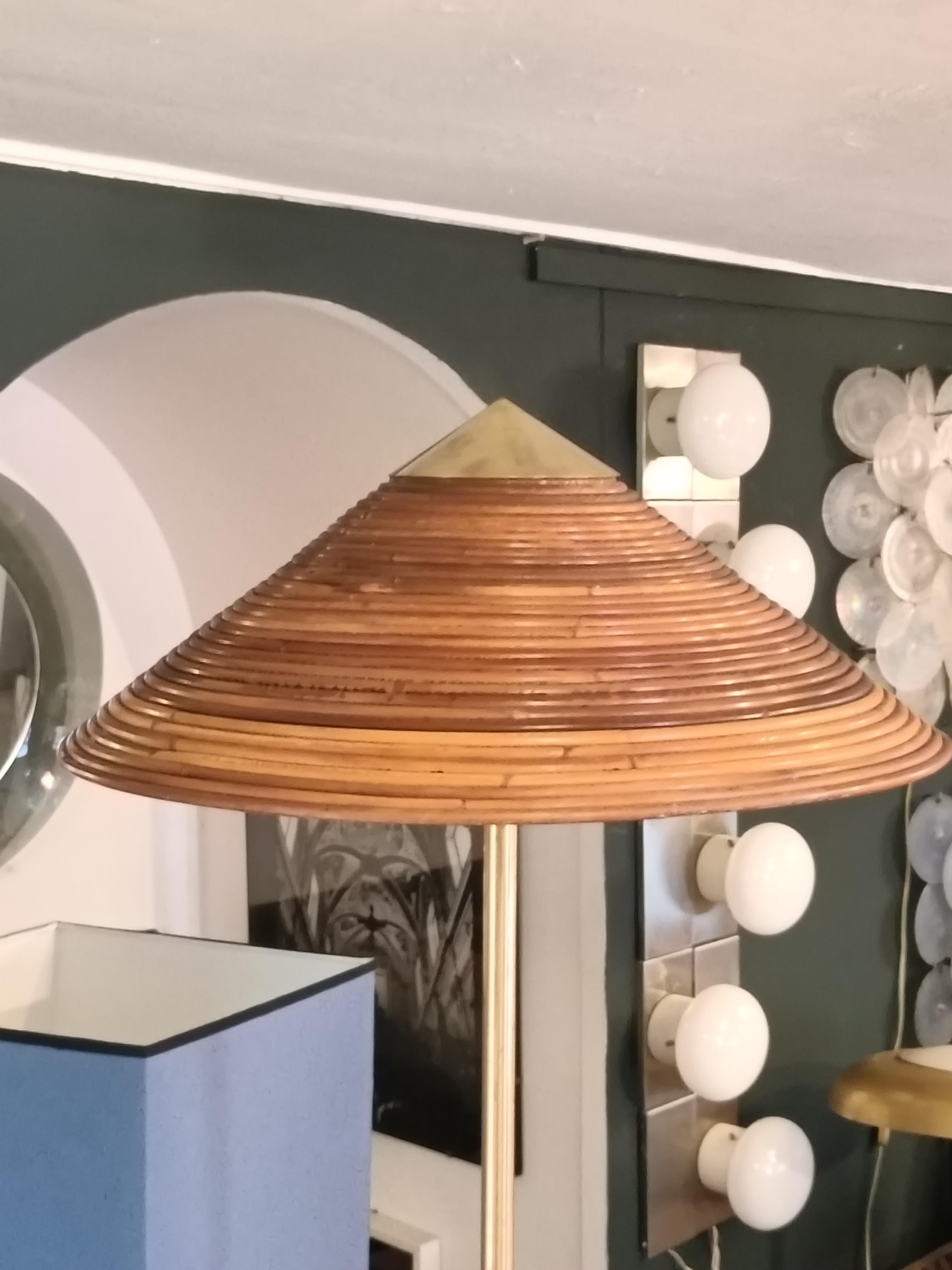 Lampada da terra realizzata in ottone  con un paralume in bambù sormontato da un terminale in ottone. Caratterizzata dal suo paralume elegante e arioso bilanciato da uno stelo in ottone laccato proietta una luce calda e ambientale in qualsiasi