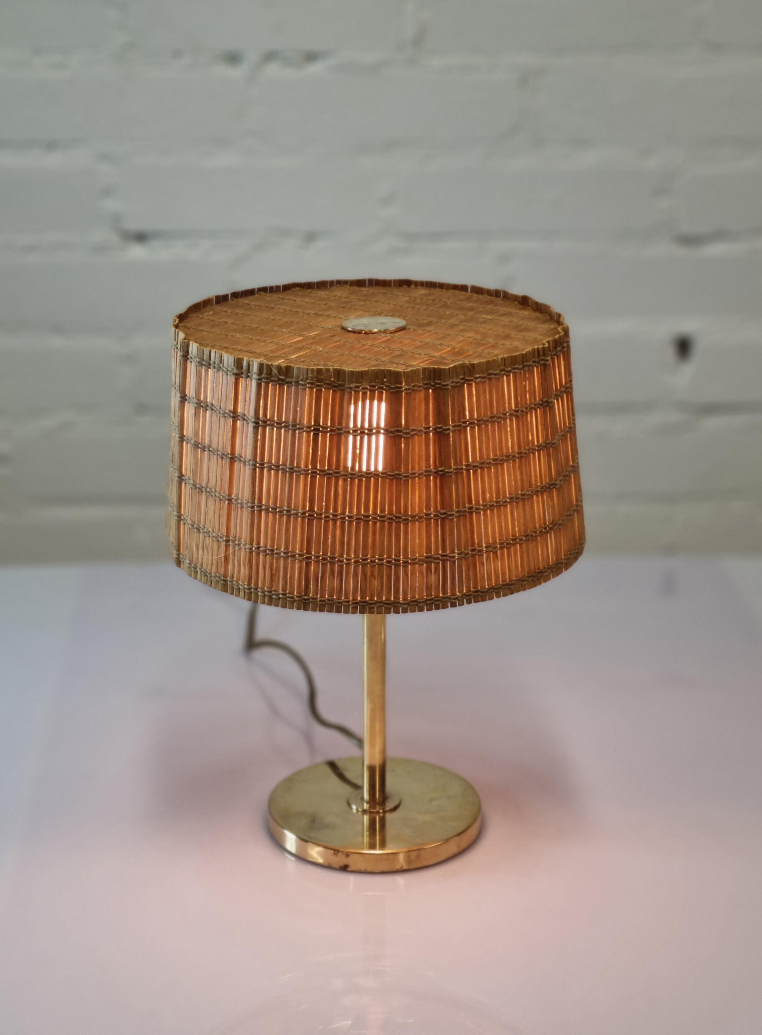 A beautiful bijou early Tynell lamp in solid brass. Simple, elegant and can be easily moved and situated in different spaces. 
The lamp is stamped Oy Taito Ab and Taito to the bottom. All parts are original and the shade is renewed with rattan. The