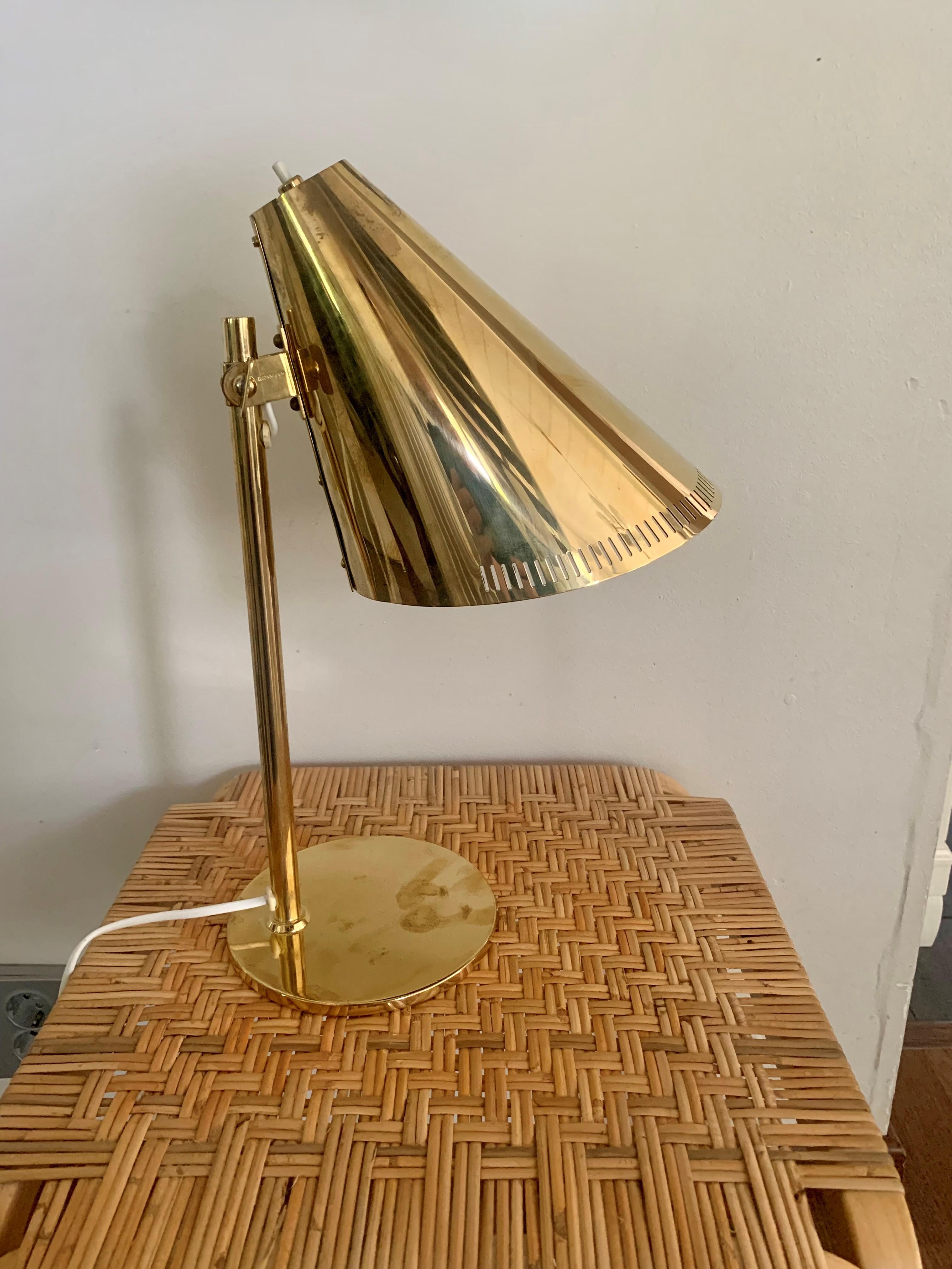 Die von Paavo Tynell entworfene Tischleuchte 9227 strahlt warmes, lebendiges Licht aus. Die Leuchte zeichnet sich durch ihren schönen, schlanken Schirm aus Messing und Glas aus, der auf einem stabilen Ständer steht. Die Tischleuchte eignet sich