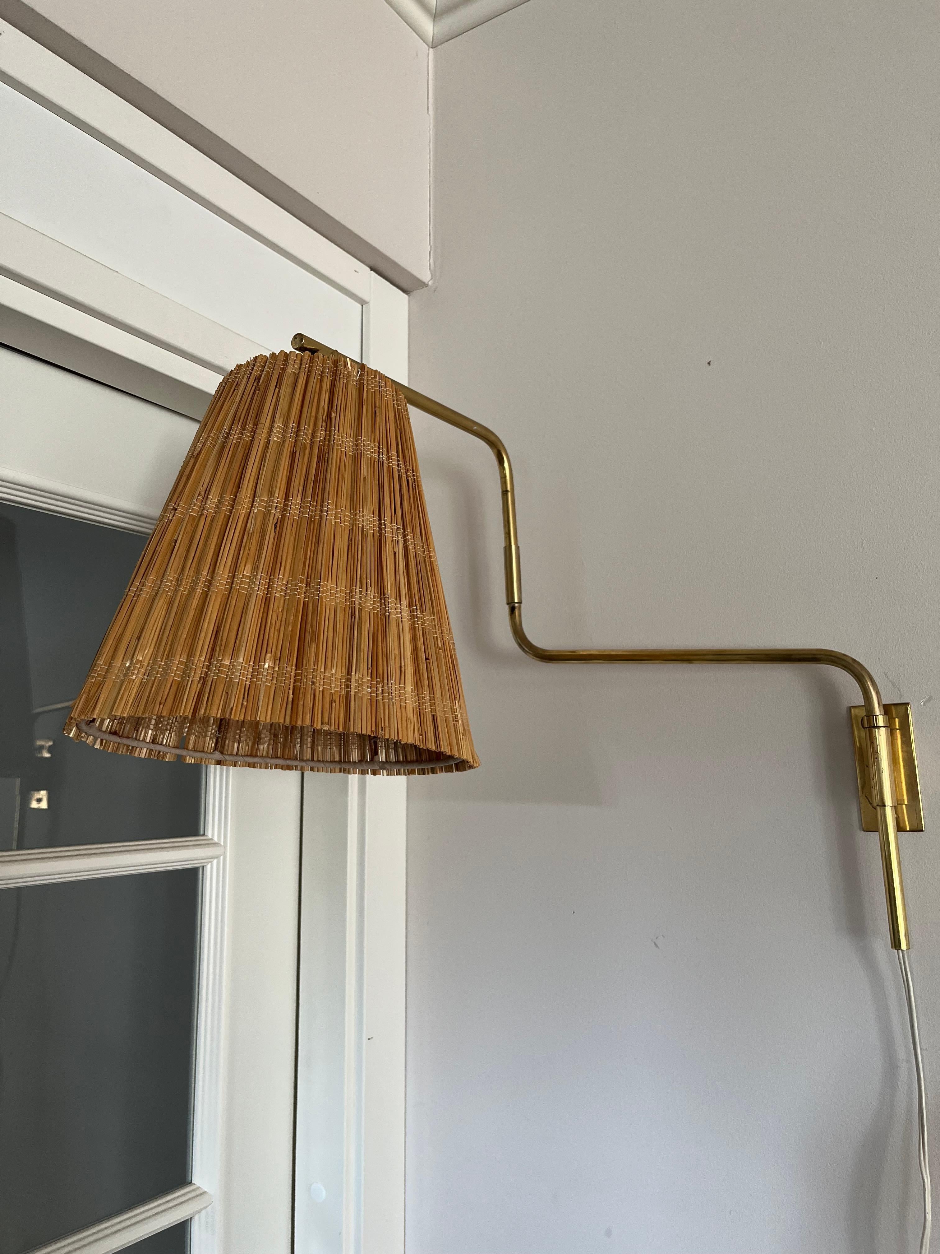 La lampada da parete **9414** disegnata da Paavo Tynell è un apparecchio di illuminazione elegante e pratico che riflette il suo riconoscibile linguaggio di design. Questa lampada è realizzata in **ottone** e dispone di un **braccio regolabile** che