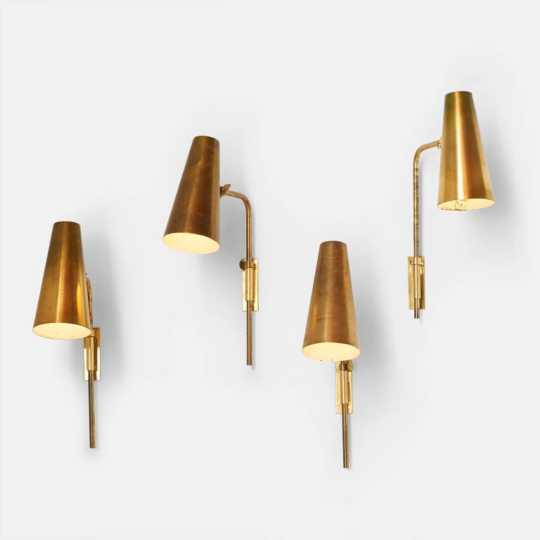 A pair of brass cone shaped wall lights with white lacquered interior by Paavo Tynell for Taito, model #9459. The height is adjustable on the wall mounted bracket as well as the angel of the brass shade. One pair left. Stamped 