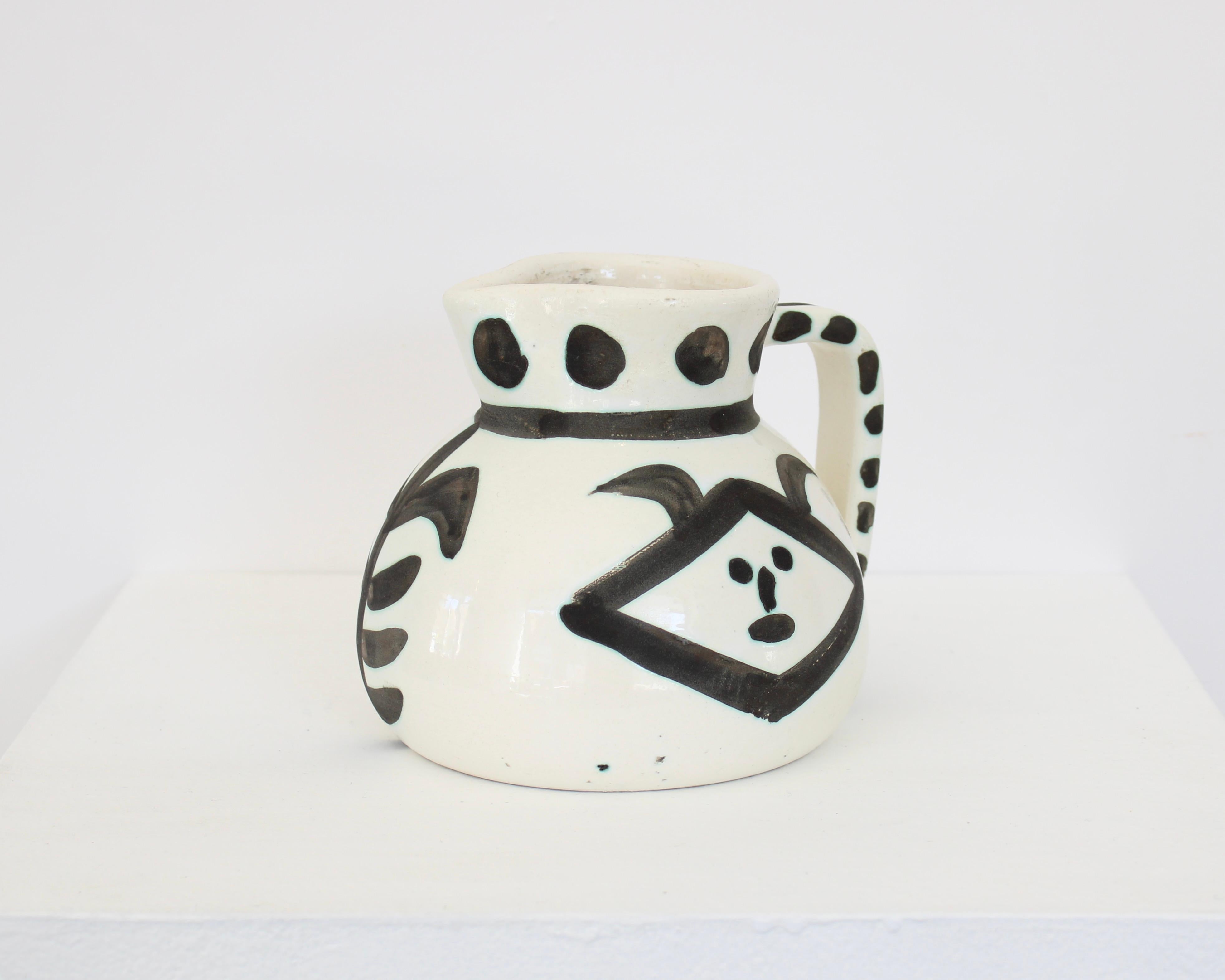Madoura turned pitcher of white earthenware clay with decoration by Pablo Picasso black and white drawings. This work is stamped with the 'MADOURA PLEIN FEU' and 'EDITION PICASSO' pottery stamps on the underside. c1956
Excellent condition with no