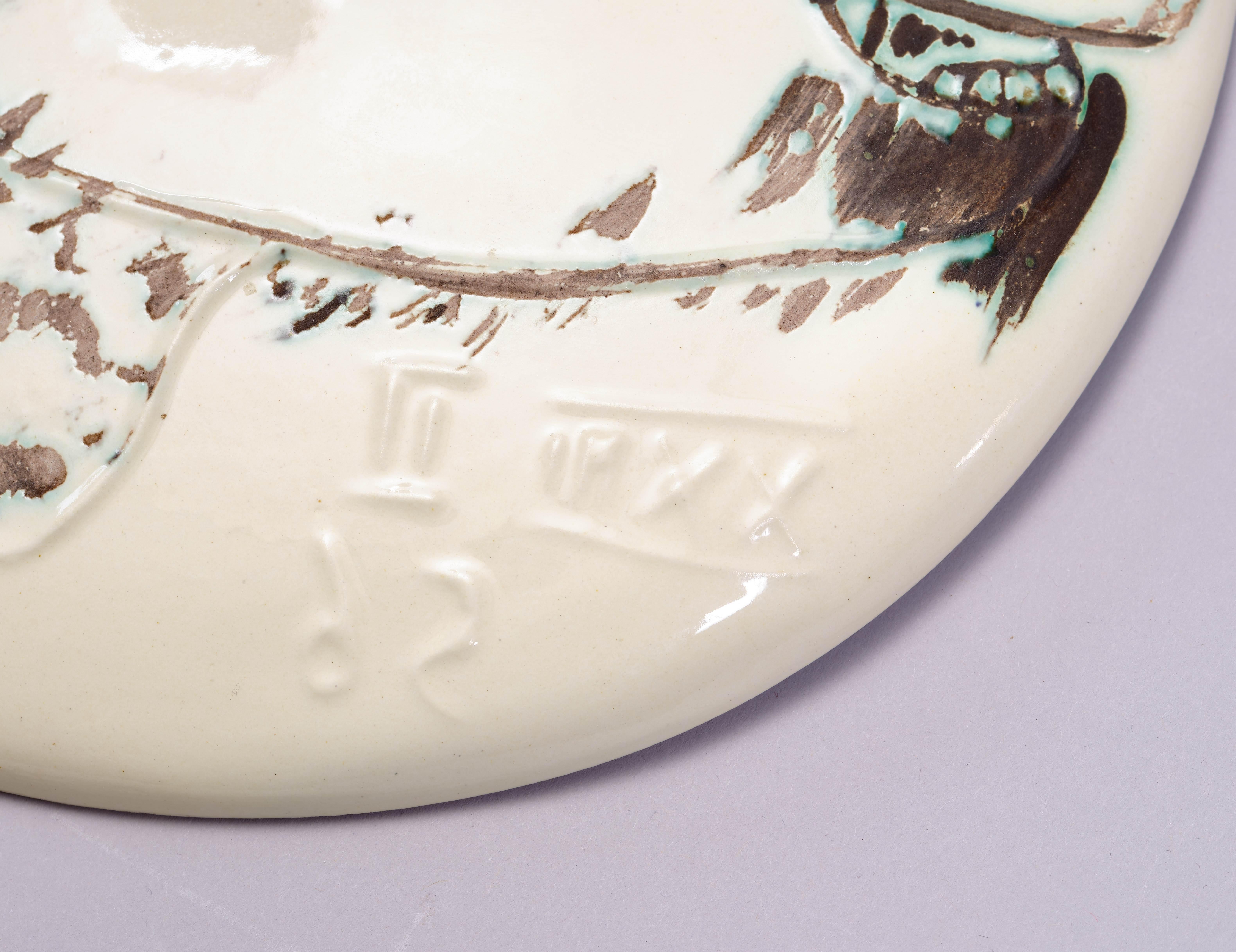 Ceramic plate painted in green, brown and ivory, 1956. Decorated with engraving and oxidised paraffin. From the edition of 450. Incised with the mirror-inverted date XXII II 56 lower right. Stamped MADOURA PLEIN FEU and EMPREINTE ORIGINALE DE