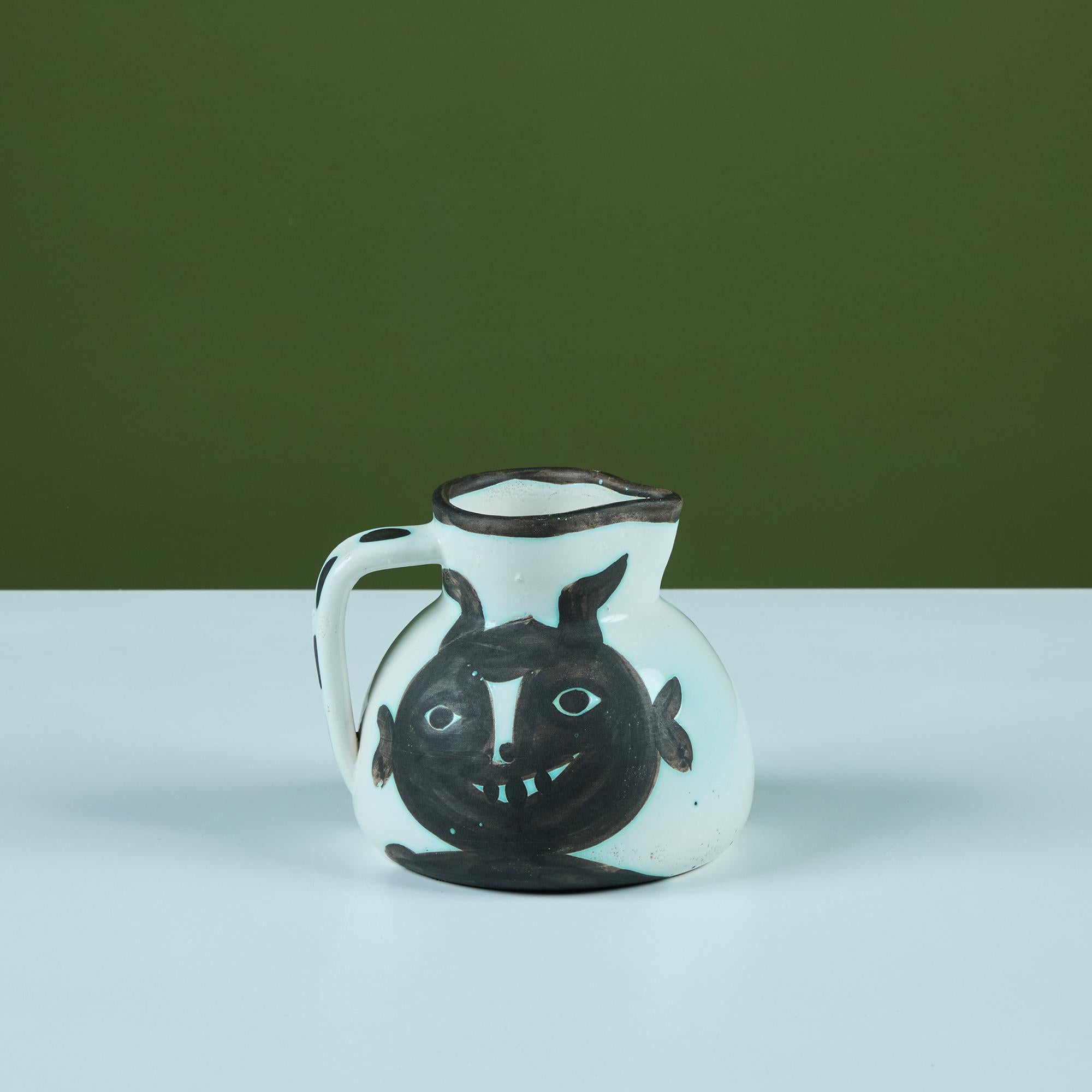 Earthenware pitcher by Pablo Picasso 1950's edition. The pitcher features two different figures on each side of the pitcher, in both a black oxidized and white glaze.

Dimensions
6.5