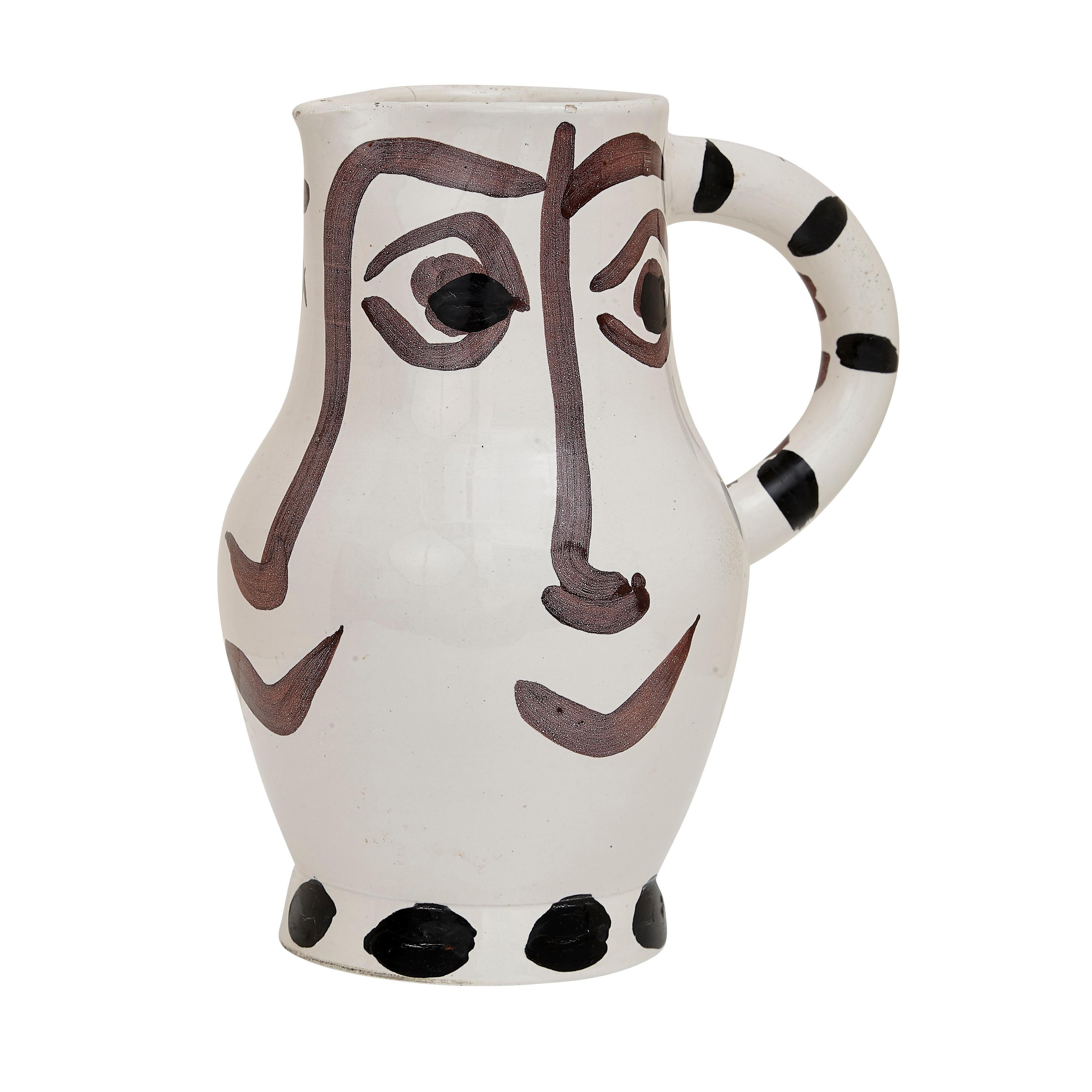 PABLO PICASSO (1881-1973) 
Quatre visages (A. R. 436)

Terre de faïence pitcher, 1959, numbered 216/300, inscribed 'Edition Picasso' and 'Madoura', glazed and painted, with the Edition Picasso and Madoura stamps.