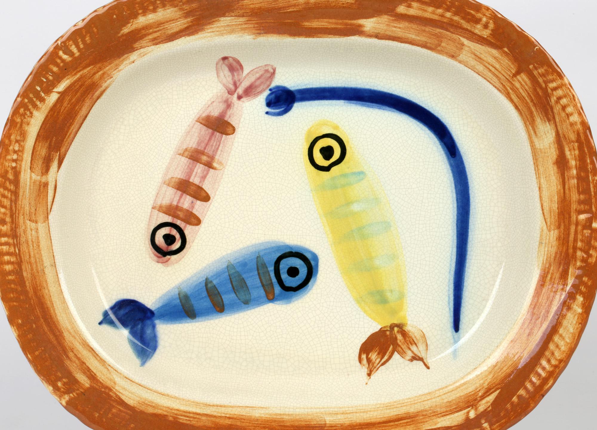 A French Terre de faience dish hand decorated with the Quatre Poissons Polychromes (Four Polychrome Fishes) design by Pablo Picasso and created in 1947. The oval shaped dish is made in a white earthenware clay and hand decorated with four fish in