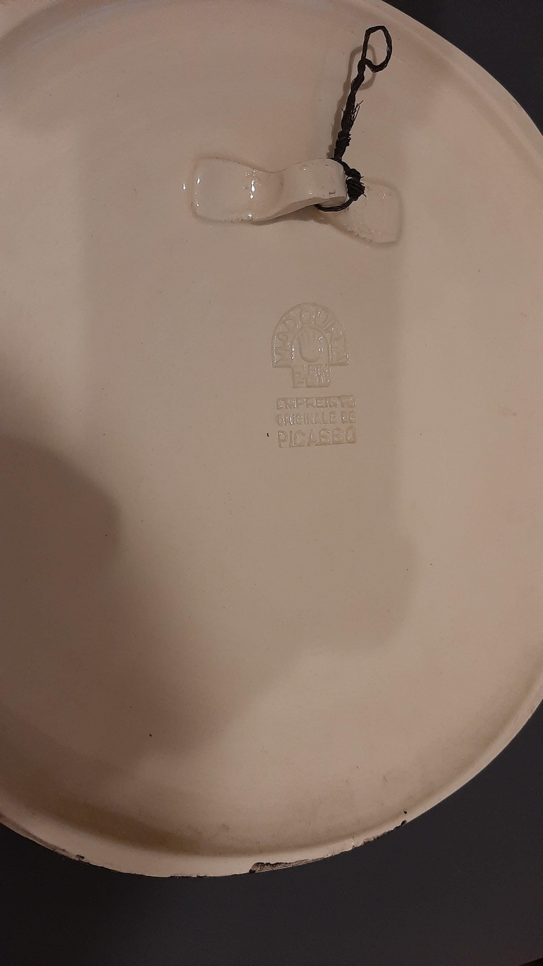 Placca da parete convessa in terre-de-faïence parzialmente vetrata e dipinta in bianco e nero, 1956. Edizione di 450 esemplari. Con i timbri Madoura Plein Feu e Empreinte Originale de Picasso, verso. 

Catalogo ragionato di riferimento: Ramié 313.