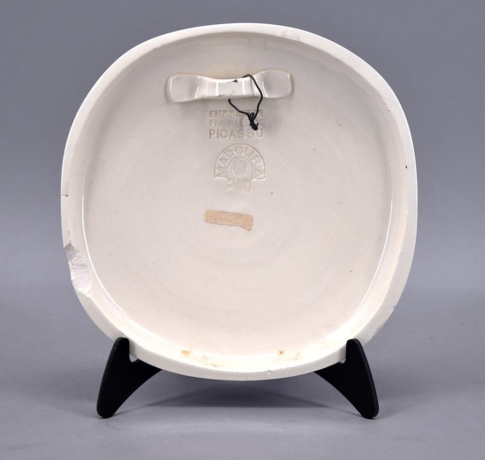 Created in 1956, this Madoura small convex wall plaque of white earthenware clay with engraving accentuated with oxidized paraffin in a glaze bath (ivory, brown) is from the edition of 500. This work is stamped with the ‘MADOURA PLEIN FEU’ and