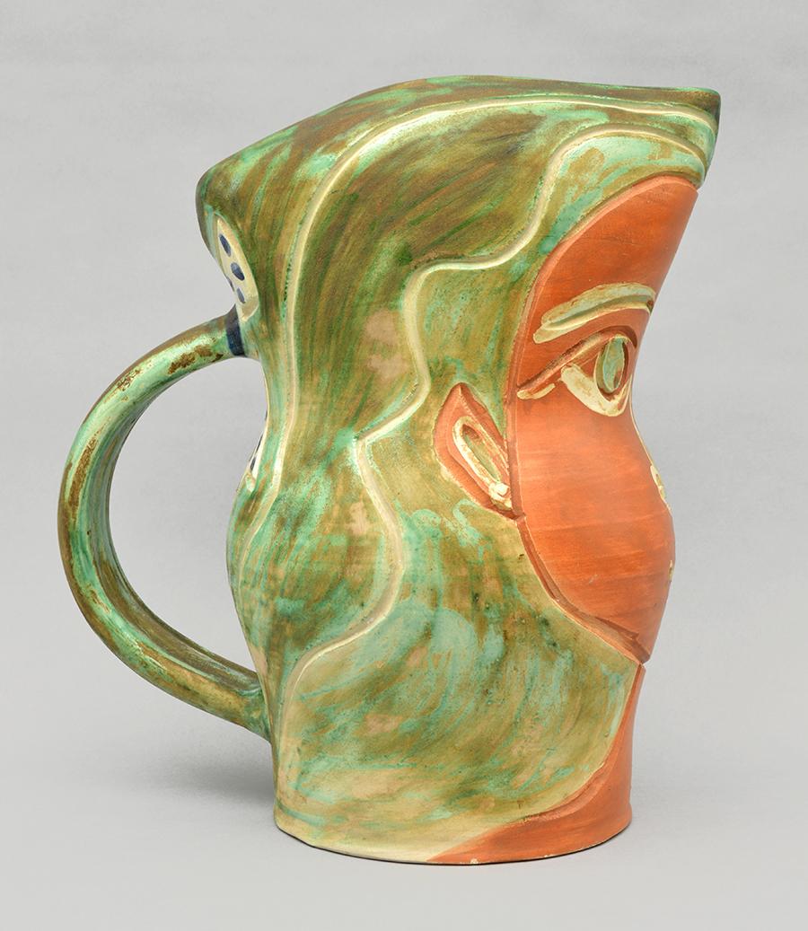 La céramique de Pablo Picasso, Visage de femme, 1953, est un pichet aux couleurs vibrantes, décoré de verts saturés contrastant avec des bruns châtains et un blanc austère. Le visage de la femme apparaît avec élégance et naturel contre la forme du