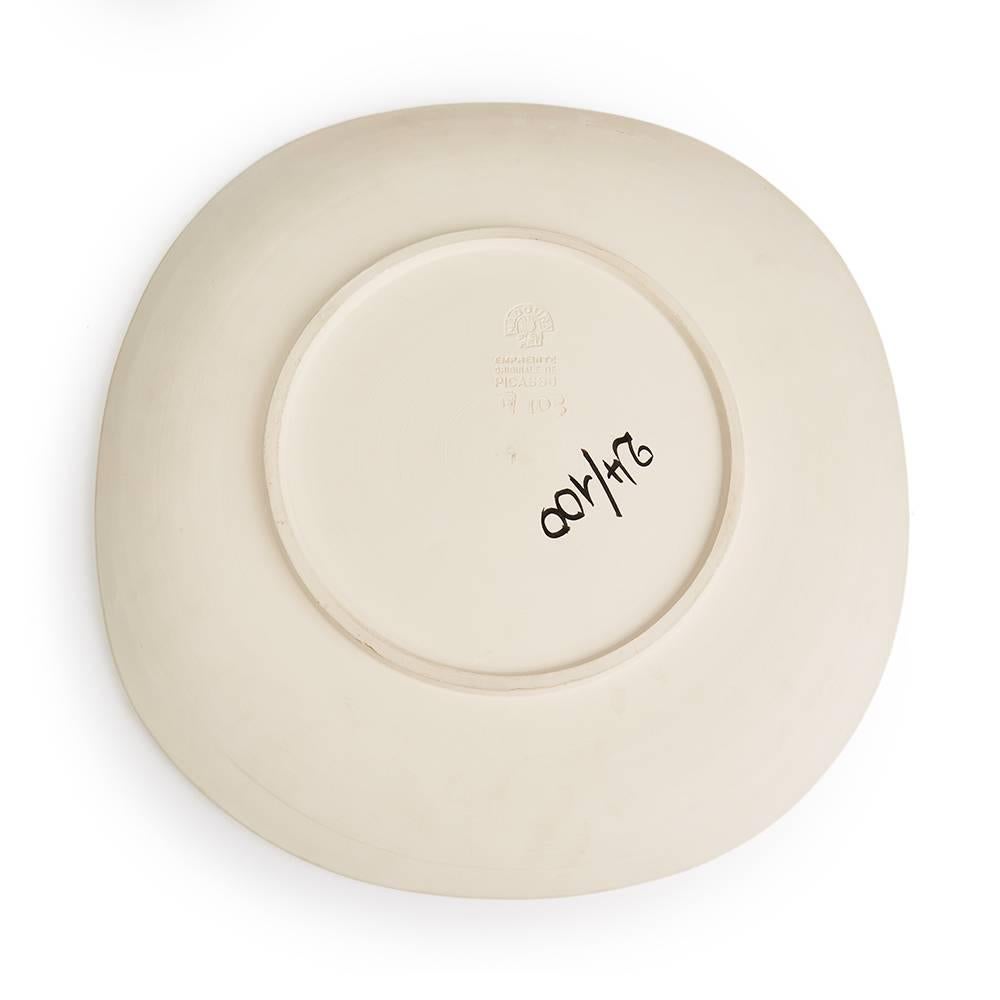 Terre de faïence dish 1956, numbered 24/100 with workshop numbering and the 'Empreinte Originale de Picasso' and 'Madoura' stamps to the base. The dish features an abstract relief face design which has been applied to the surface of the dish. This