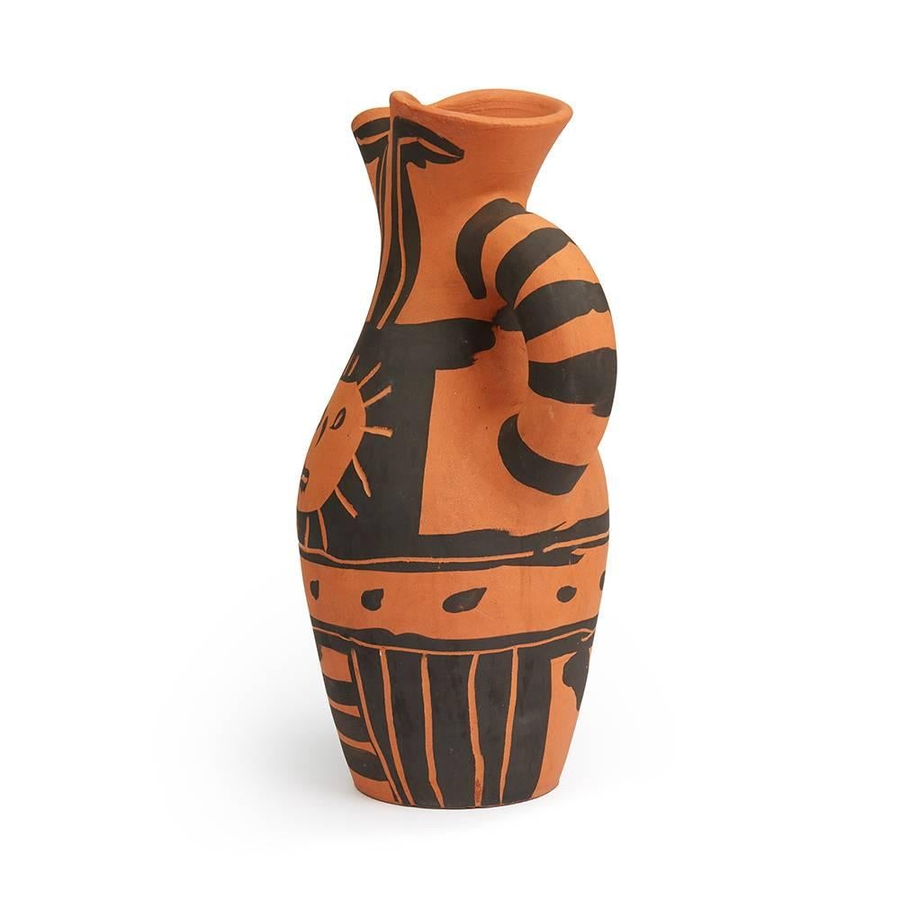 Terre de faïence 1963, numbered 3/300 and incised with 'Empreinte Originale de Picasso' & 'Madoura' stamps.

The earthenware pitcher has been decorated with a simplistic black oxidised paraffin design featuring two charismatic suns on either side