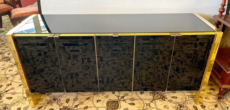 Sleek and sexy late 1970's Pace Furniture black glass and gold chrome credenza. A multi-purpose marvel.
Features shelving underneath and great lines. There is some age appropriate wear and there are a couple of places where the gold chrome needs to