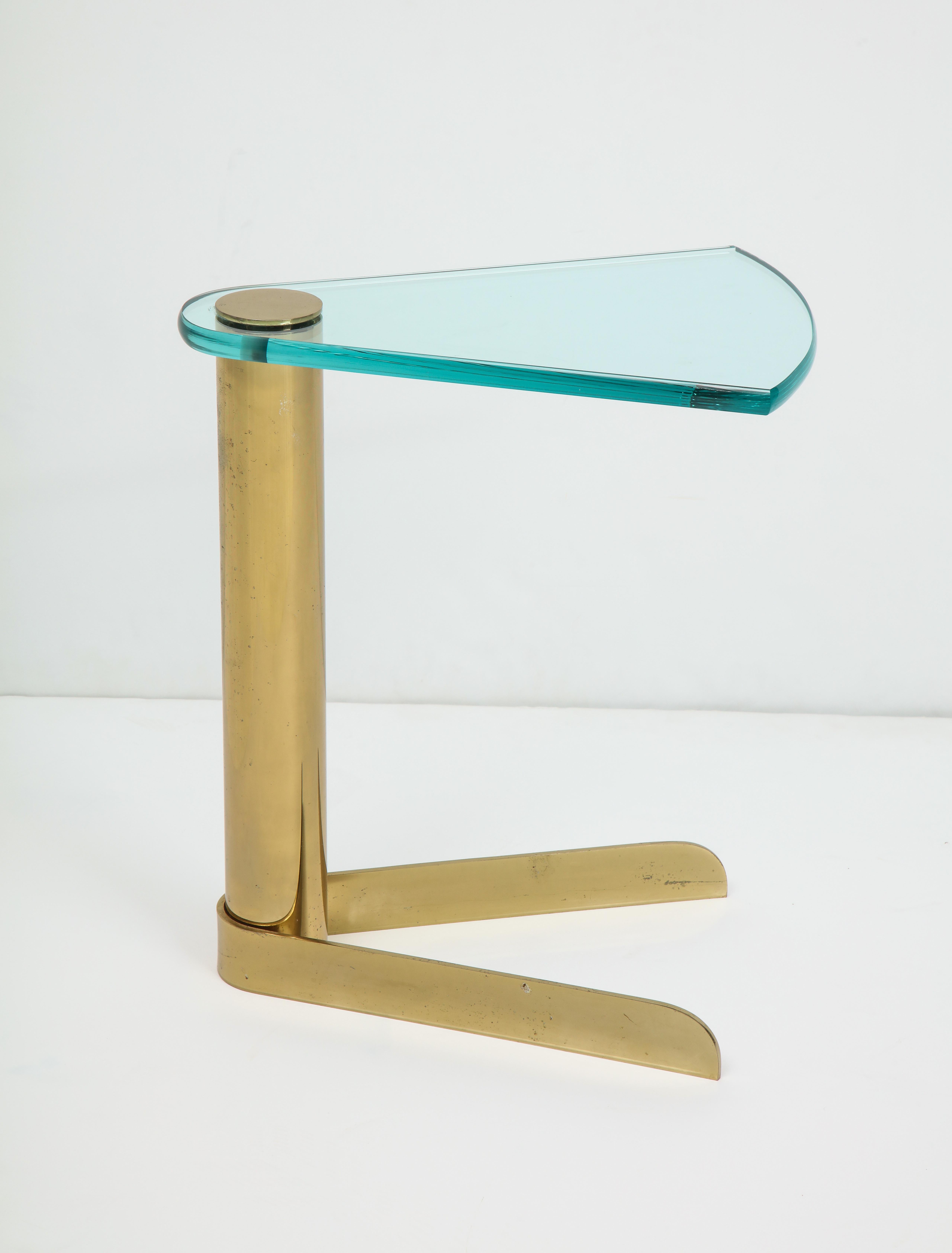 1980s chic brass cigarette/martini table with a wedge shaped glass top and brass base.