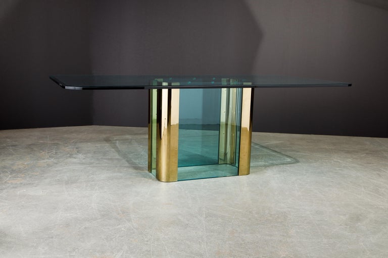 This large 1970s rectangular dining table by Pace Collection features beautiful blue glass and gleaming brass, finished with incredible detail such as the large brass screw heads which are reminiscent of Cartier. The glass top which is 3/4