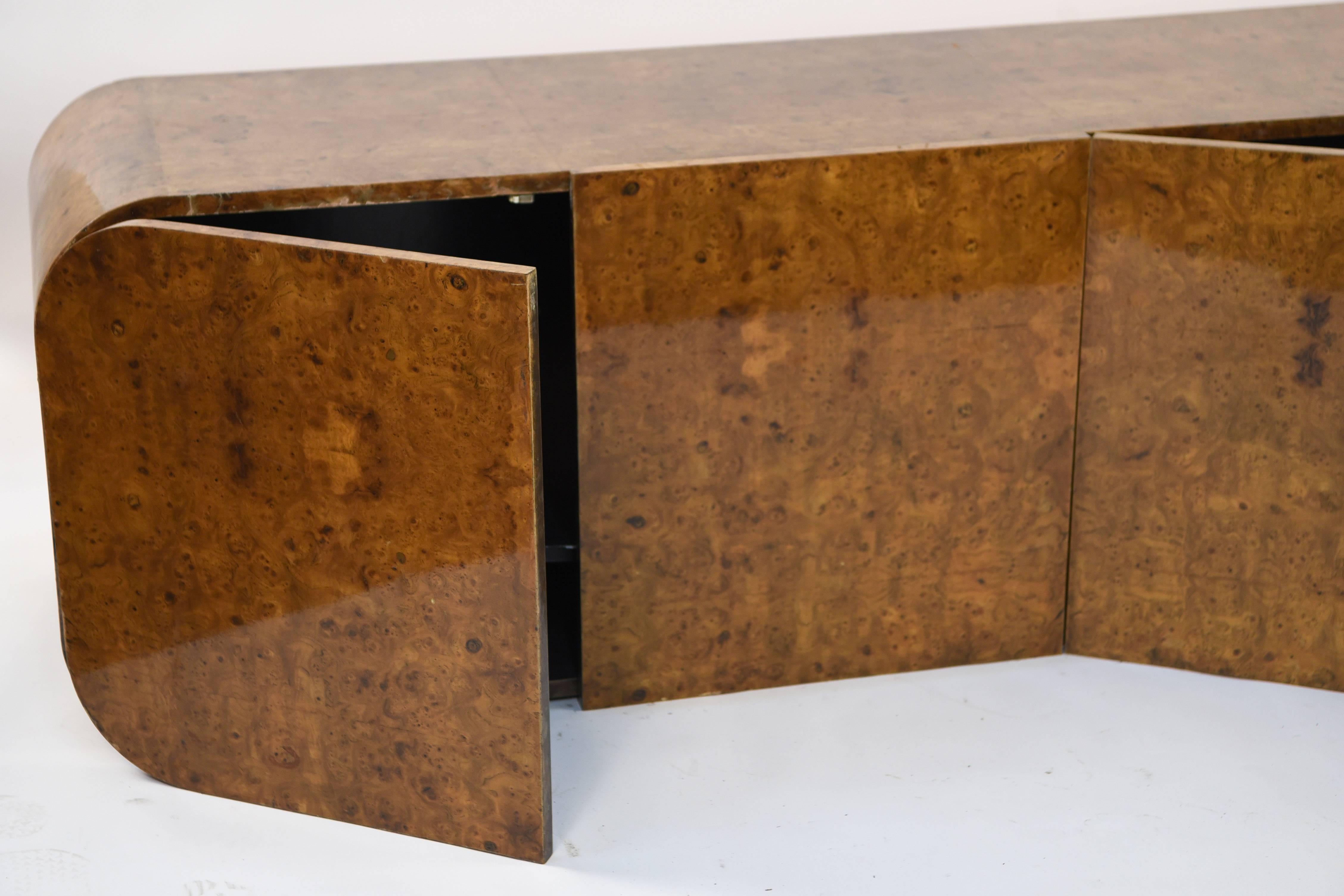 This sideboard or credenza is meant to be wall-mounted to give a modern, floating illusion. Made by Pace Furniture Collection, circa 1970s, in a gorgeous burl wood. The curved corners give this piece a sleek appearance.