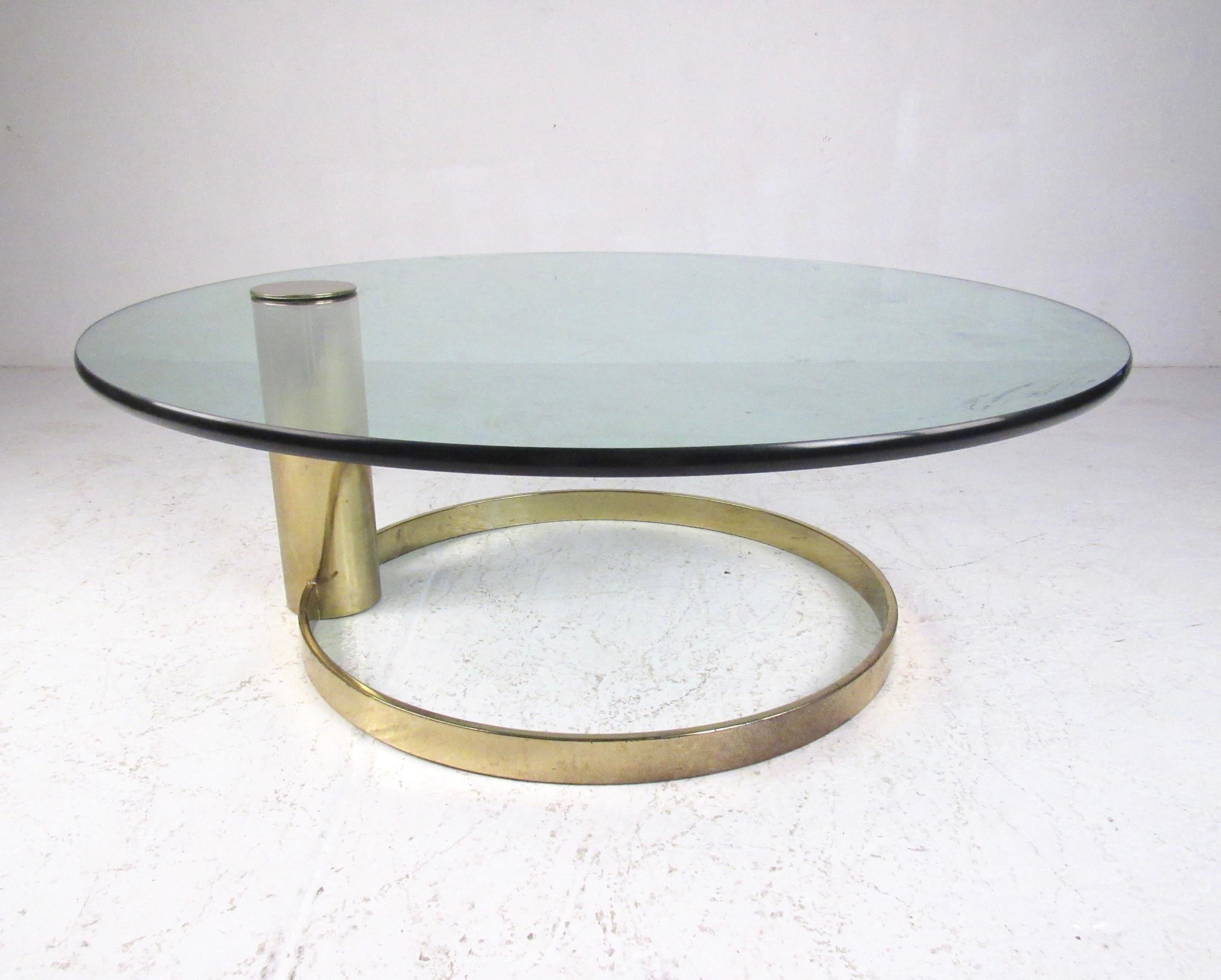 This striking vintage modern coffee table features brass plated cantilever base, thick glass top, and the striking midcentury style design of Leon Rosen for Pace collection. This circular brass plated coffee table makes an impressive addition to