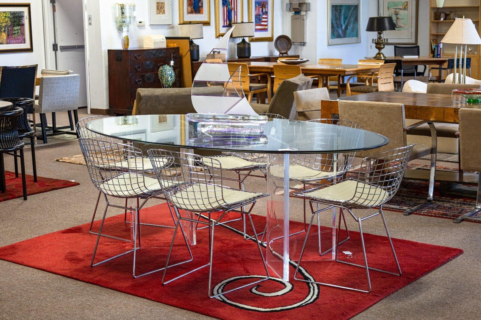 An oval and lucite dining table. This is a gorgeous contemporary modern dining table with a simple design, but a stunning presentation. This table features a very large oval glass top with a semi-smoked finish. Supporting the weight of the glass top
