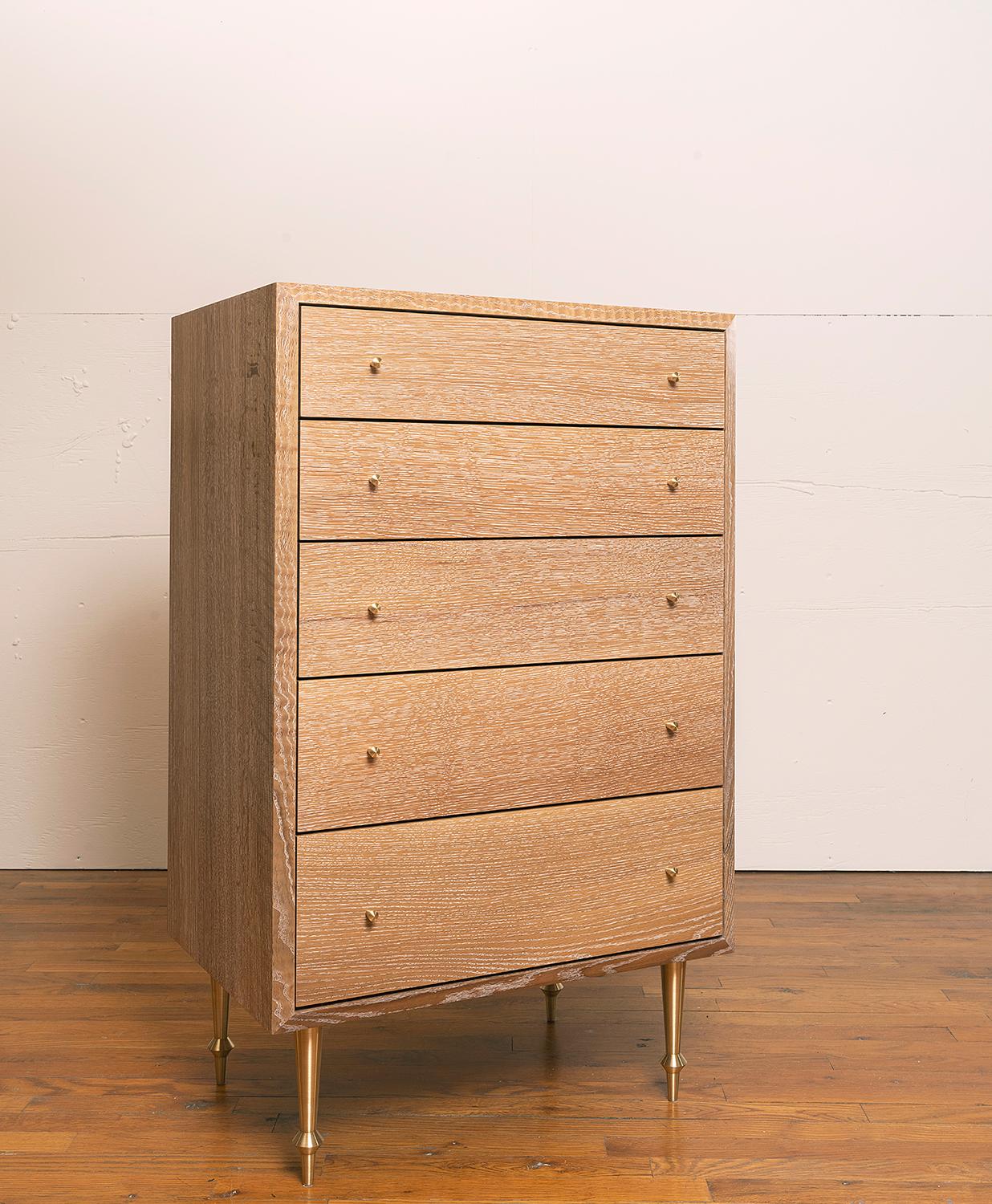 Solid white oak with turned brass legs and drawer pulls.
Cerused finish.
Dimensions: 42” H x 26” W x 18” D.
 