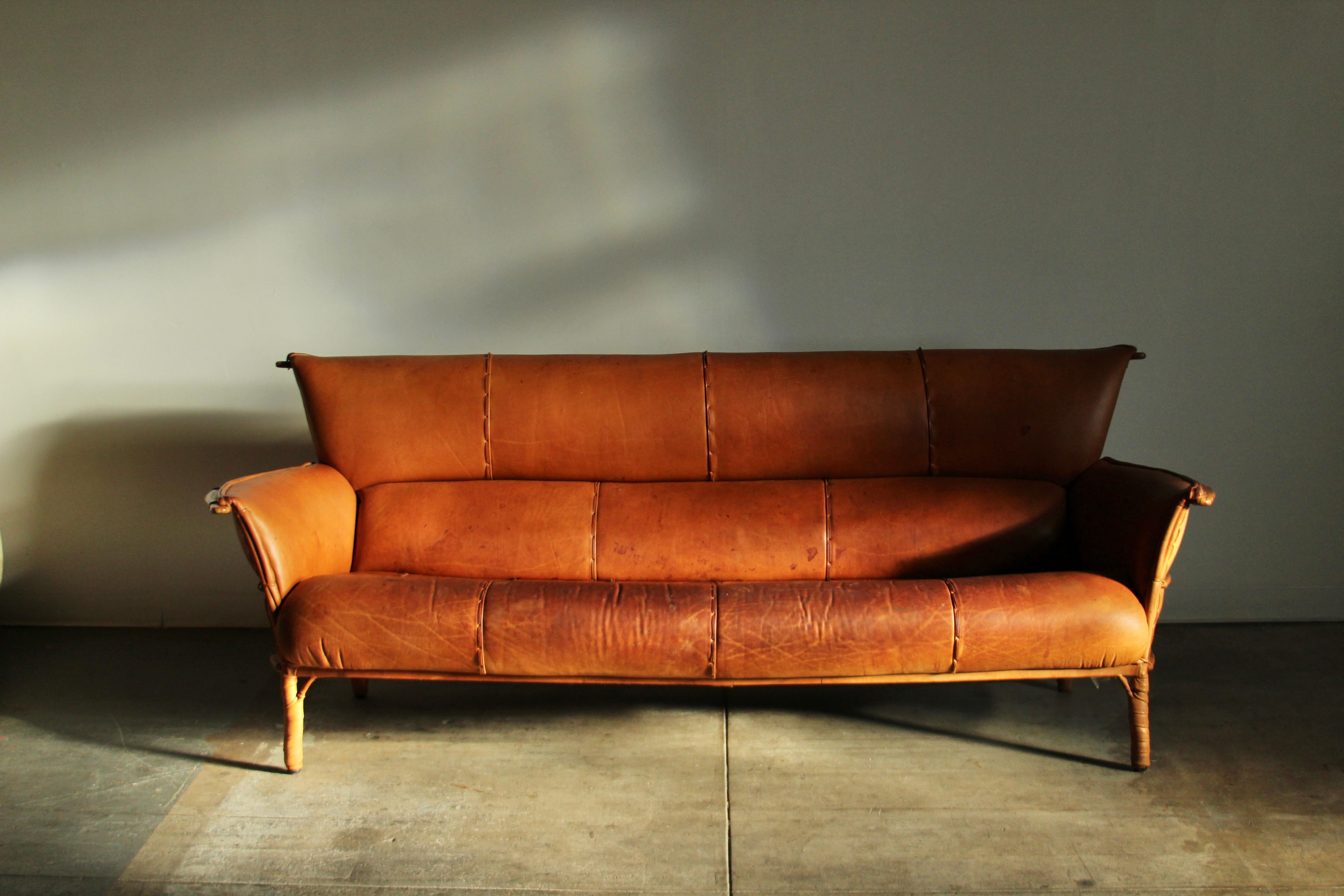 An absolutely stunning 3-seat sofa by Pacific Green in distressed cognac leather and palm wood. This sofa belongs in an amazing modernist cabin or rustic lodge. Super high quality leather shows lots of patina consistent with age and use,