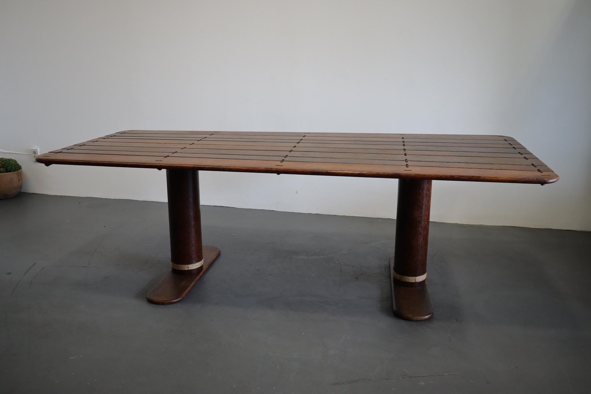 An exotic handcrafted rectangular palm wood dining table, a rare find from Pacific Green design. This piece is supported by a steel frame and embellished with the highest quality leather accents. The coconut trunk legs offer a noteworthy element to
