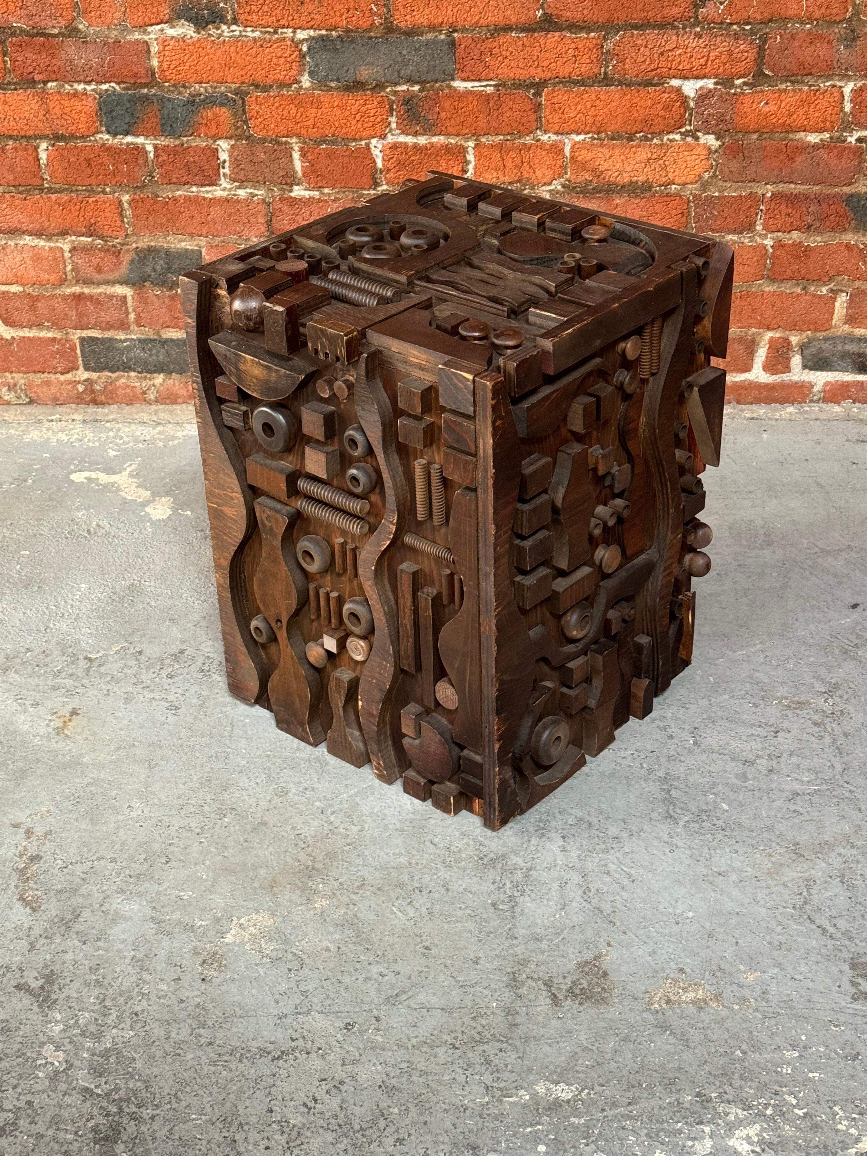 A Pacific Northwest creation circa 1970s to 1980s, plywood side table / sculpture, having various abstract designs attached to the exterior of the table / sculpture and finished with a dark brown stain.