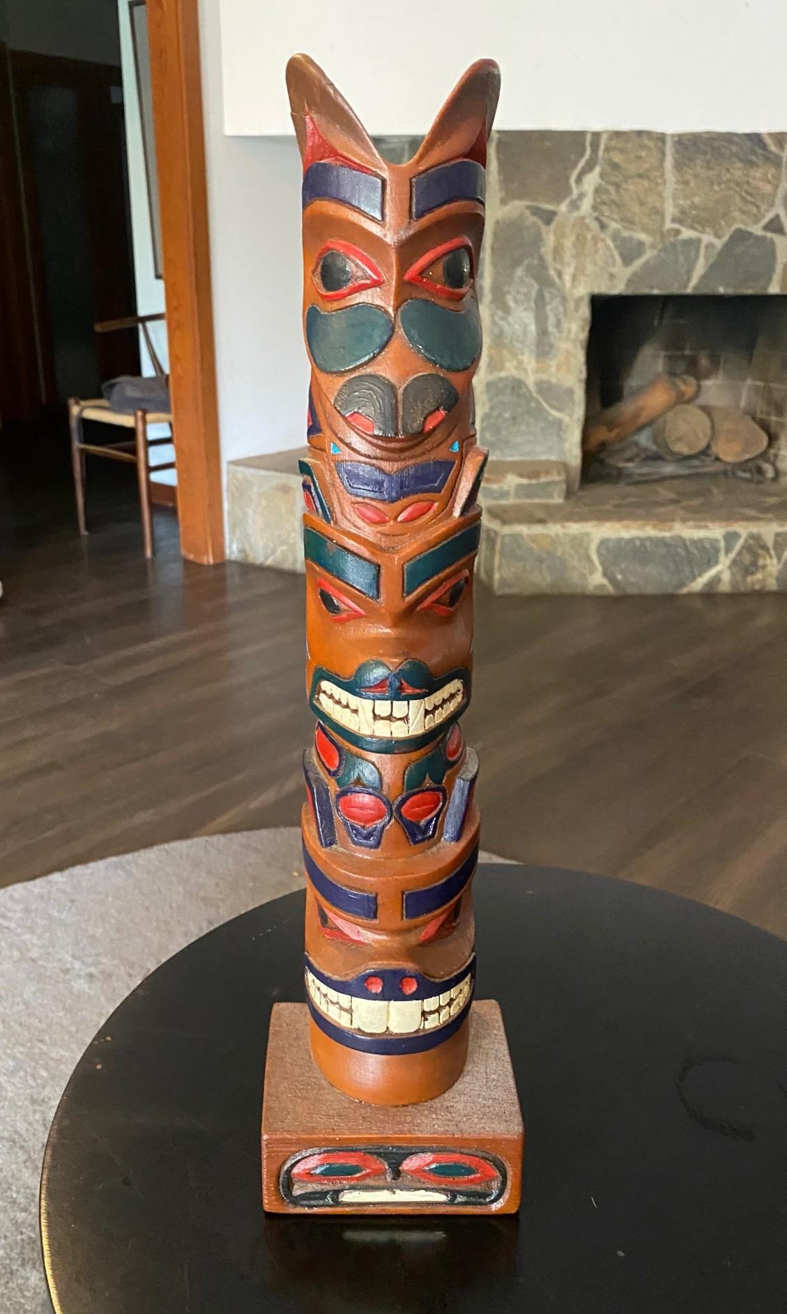 A beautifully desiged, wonderfully carved Pacific Northwest Coast First Nation Native American (perhaps Haida, Tlingit, or Nootka) indigenous hand carved wood Three-figure totem pole.  

The work is signed and dated (1980) on the base underside. 